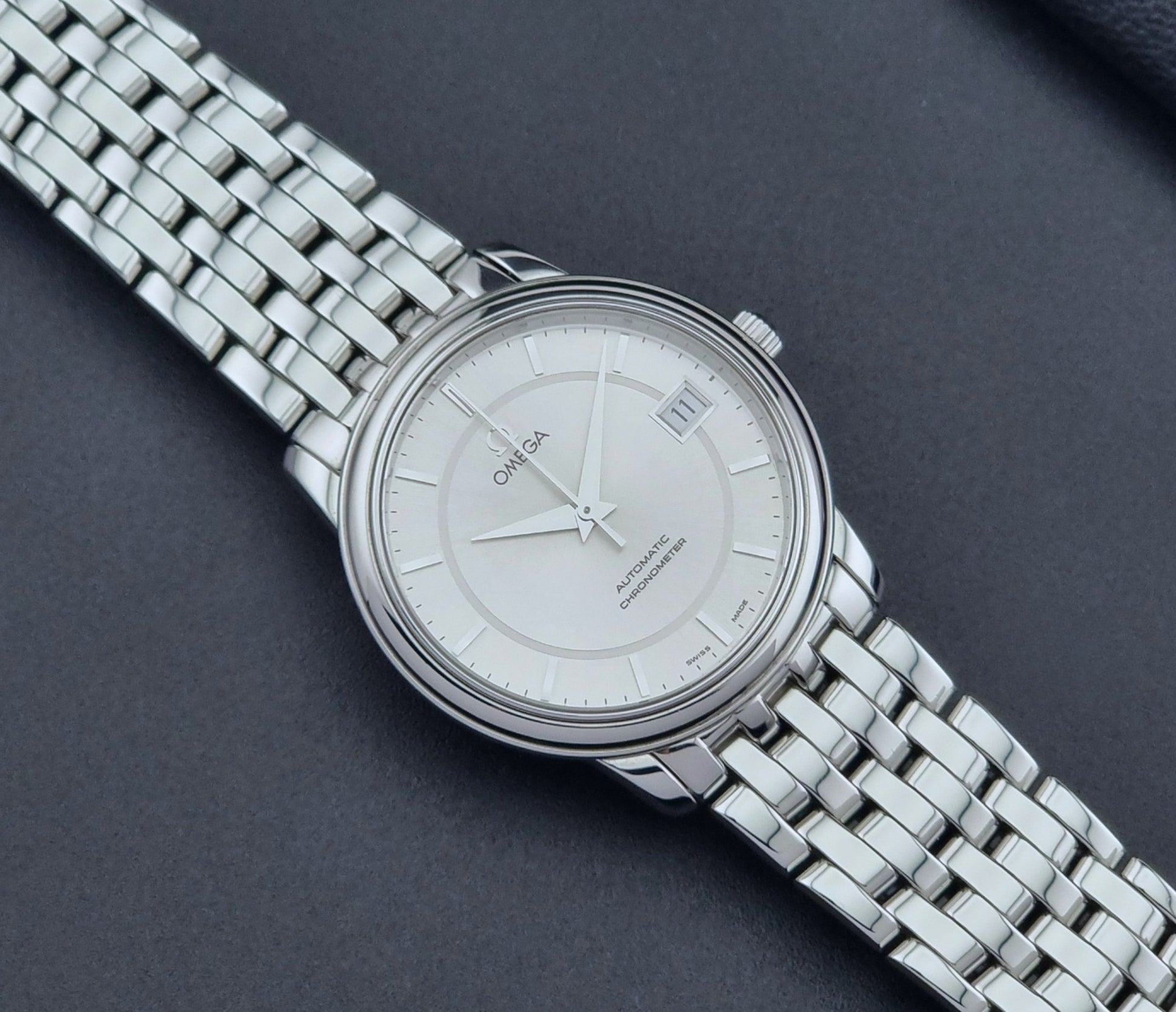 Omega watch a De-Ville Prestige 168.1050 with a stainless steel bracelet on a dark background clos eup dial view