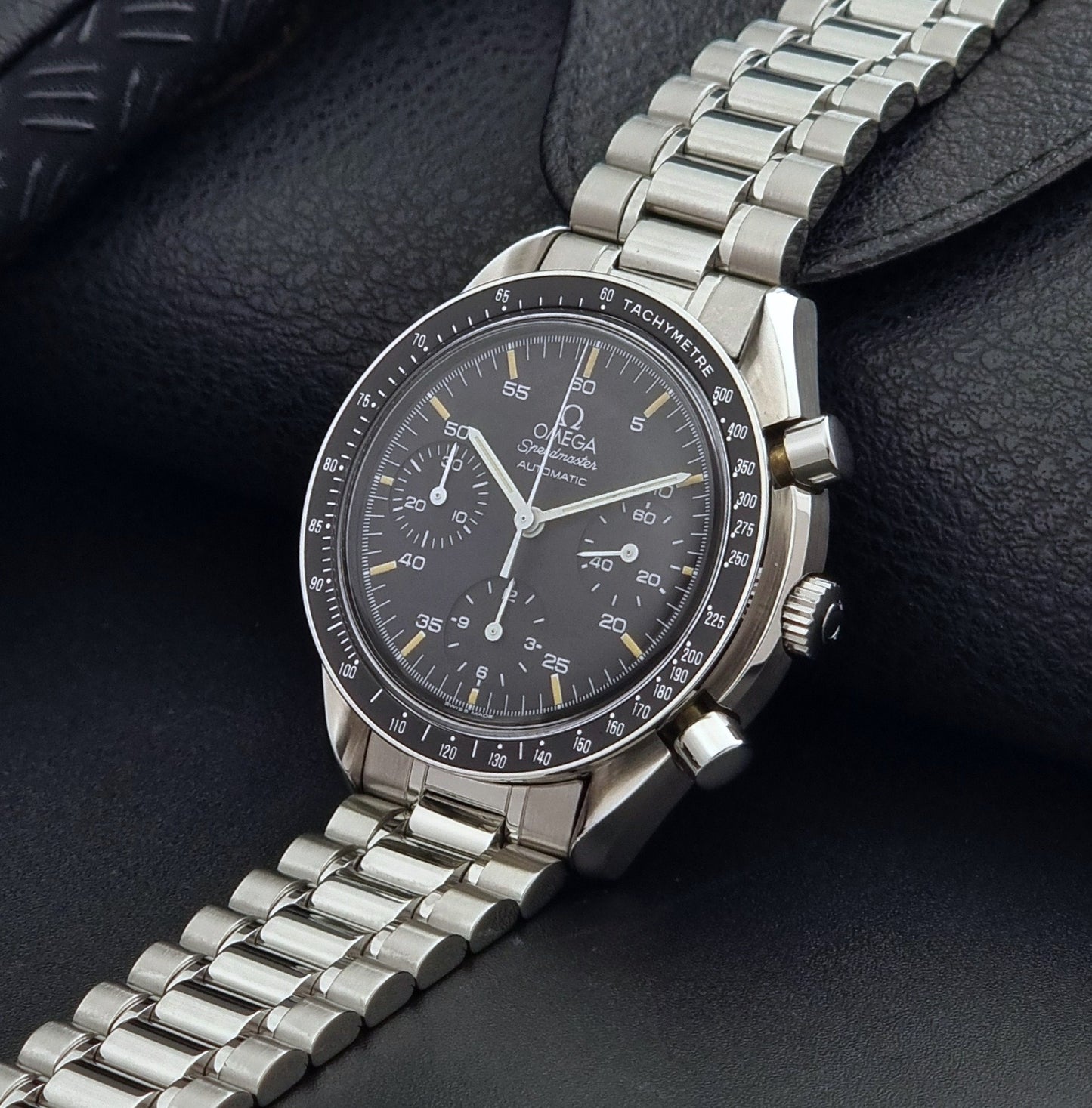 Vintage Omega watch Speedmaster Reduced 3510.50 watch with a black dial on a dark textured background crown view