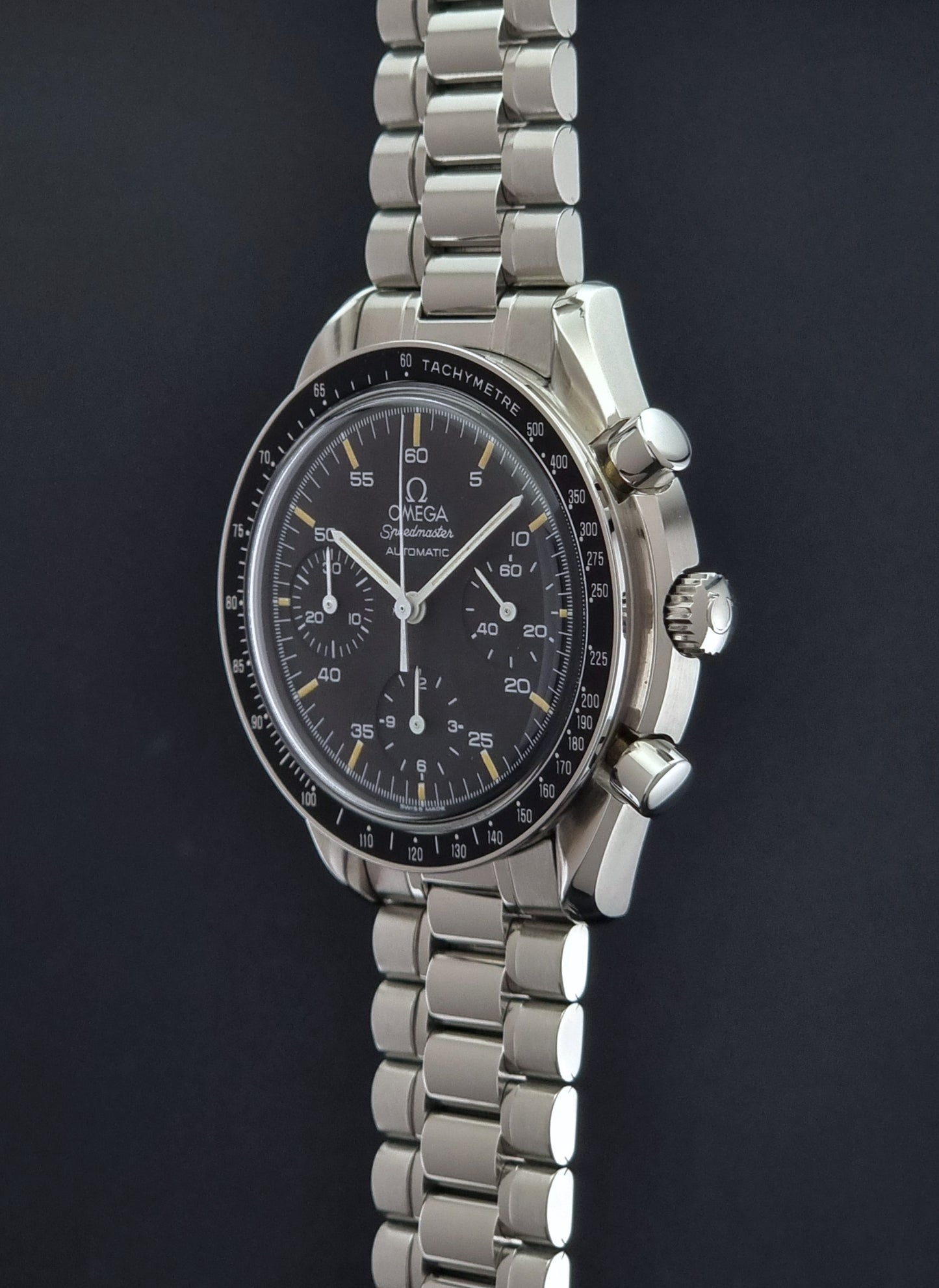 Vintage Omega watch Speedmaster Reduced 3510.50 watch with a black dial on a dark textured background crown profile view