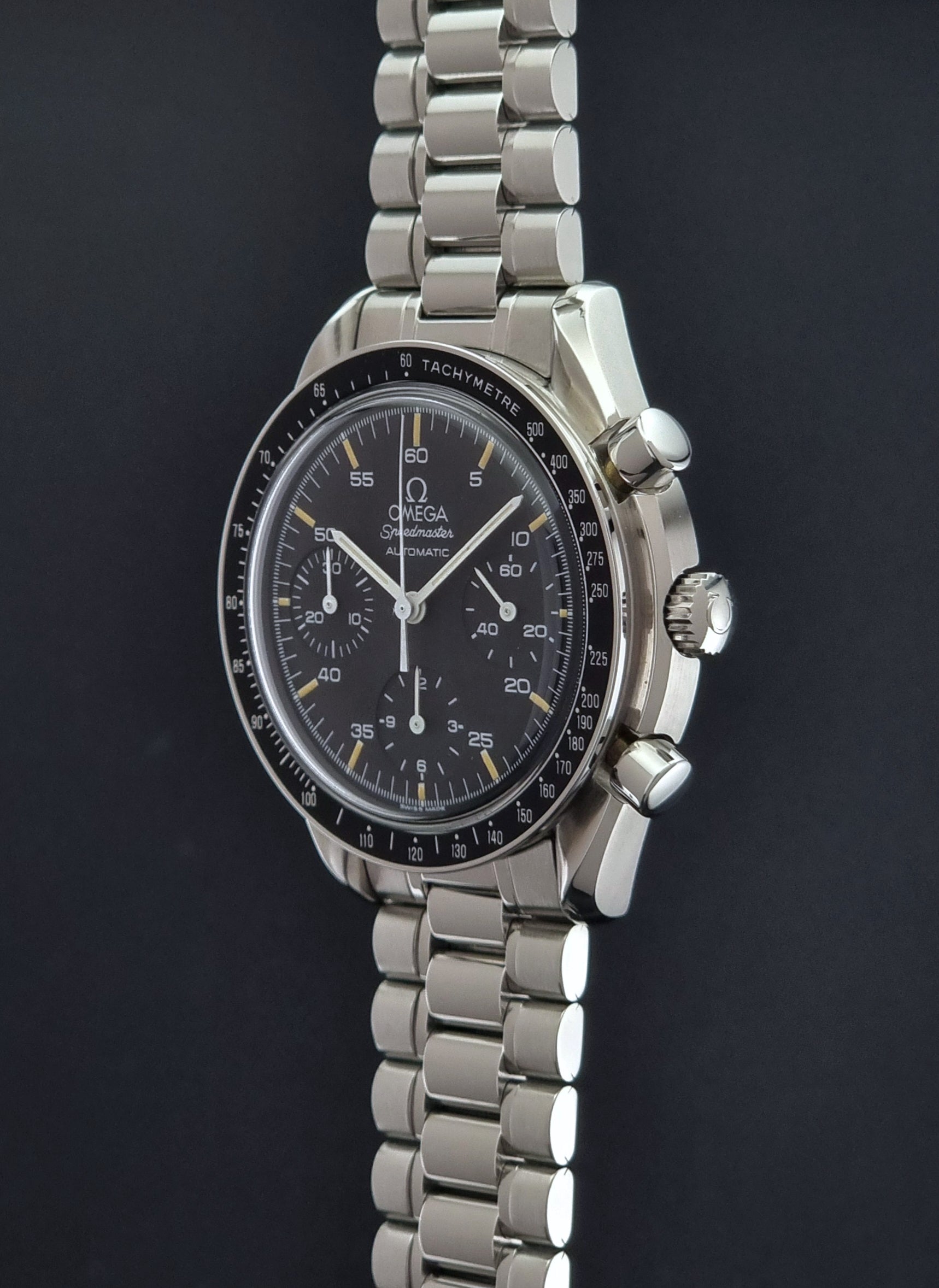 Vintage Omega watch Speedmaster Reduced 3510.50 watch with a black dial on a dark textured background crown profile view