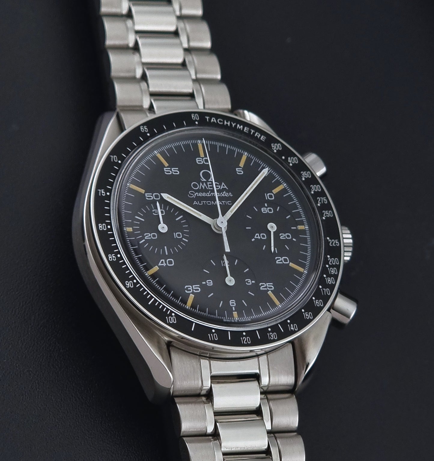 Vintage Omega watch Speedmaster Reduced 3510.50 watch with a black dial on a dark textured background front view