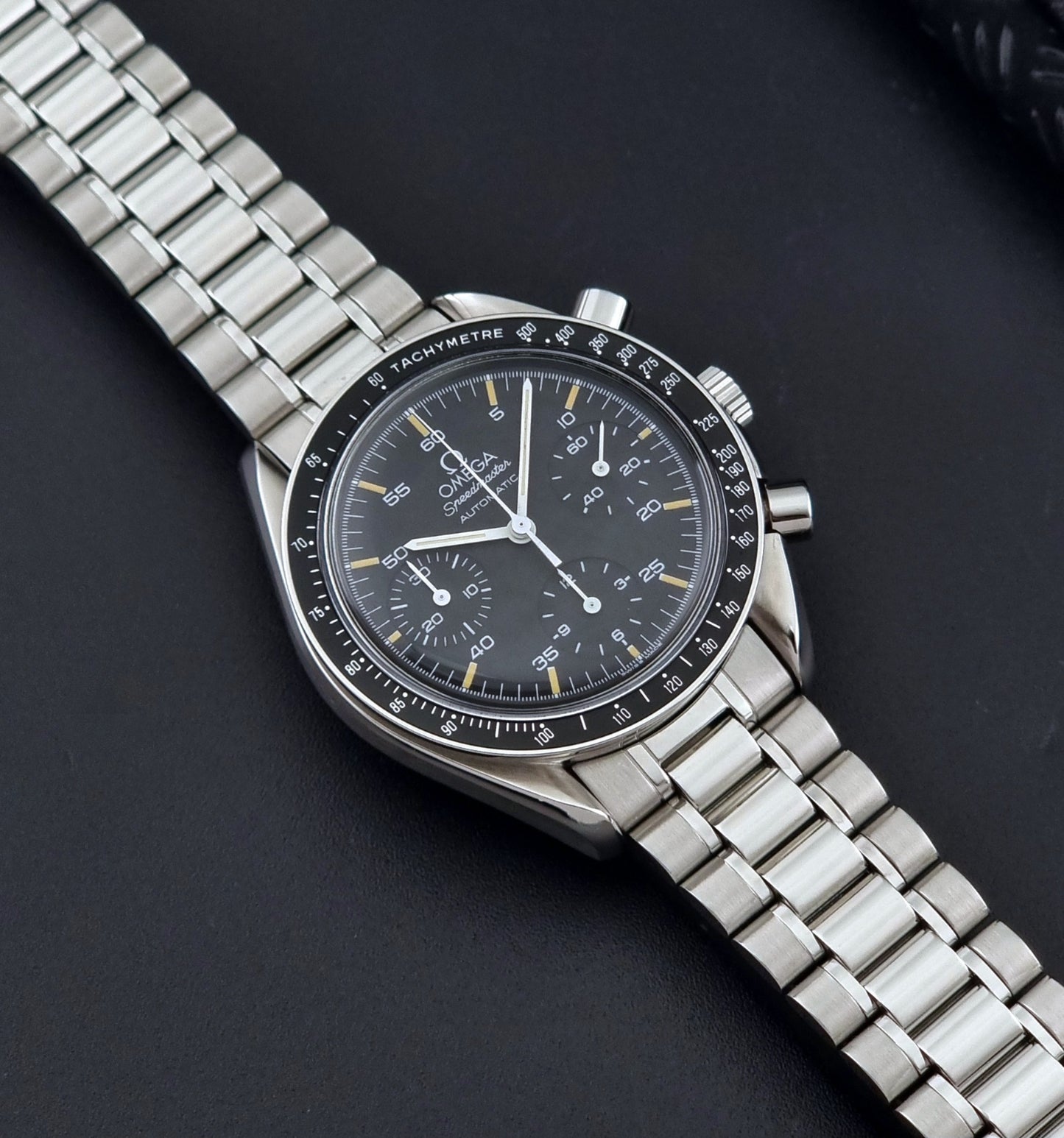 Vintage Omega watch Speedmaster Reduced 3510.50 watch with a black dial on a dark textured background dial