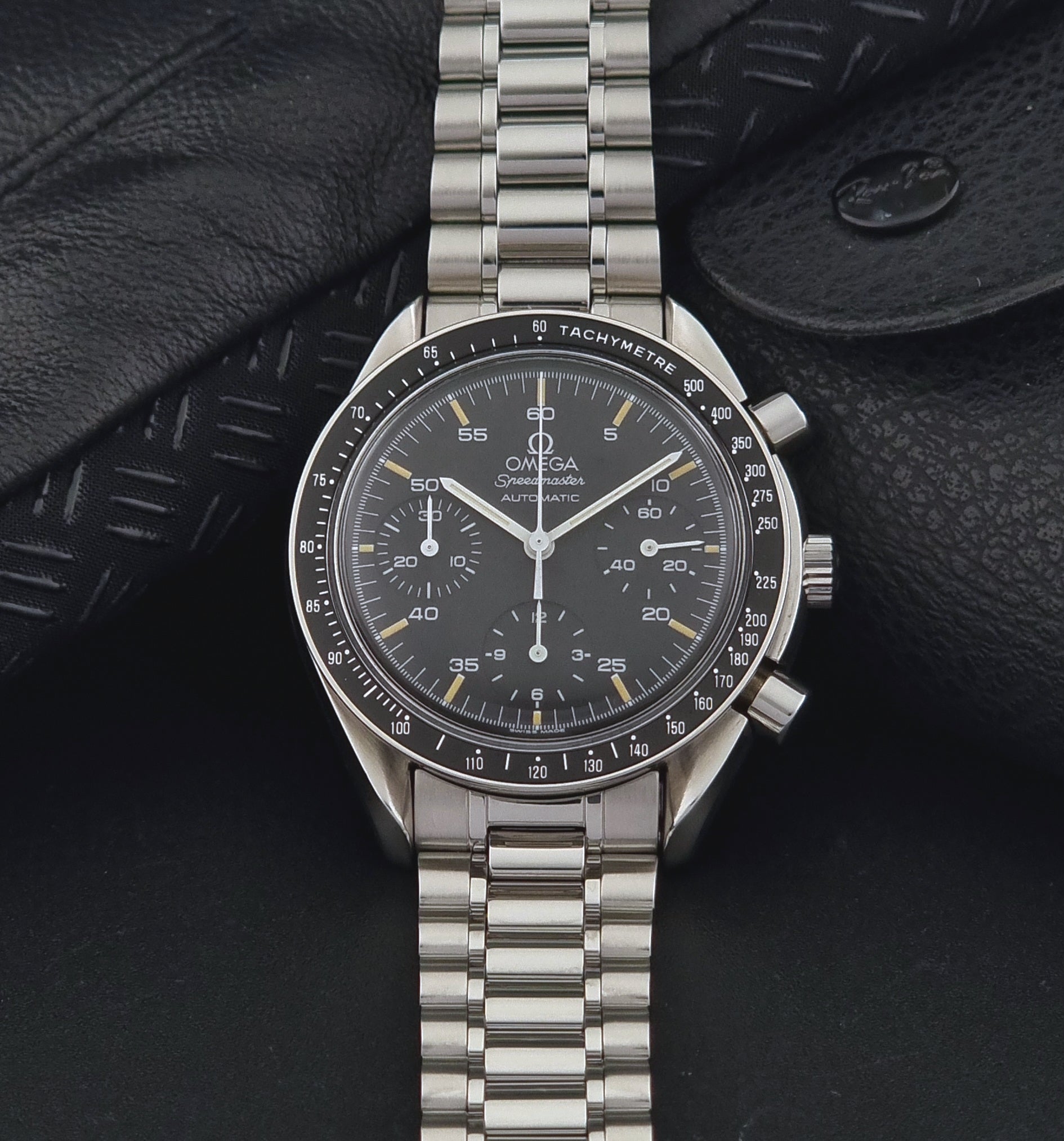 Vintage Omega watch Speedmaster Reduced 3510.50 watch with a black dial on a dark textured background dial view