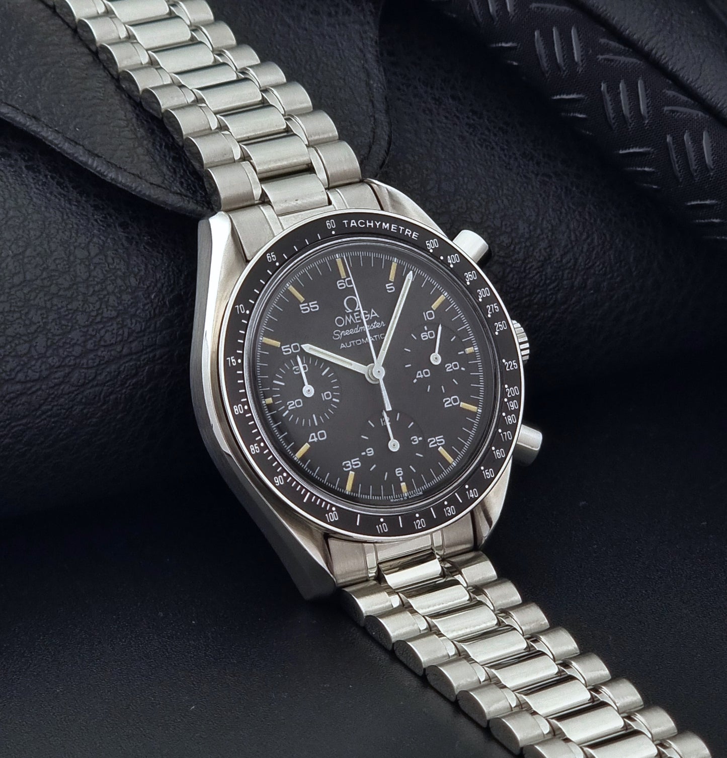 Vintage Omega watch Speedmaster Reduced 3510.50 watch with a black dial on a dark textured background side view