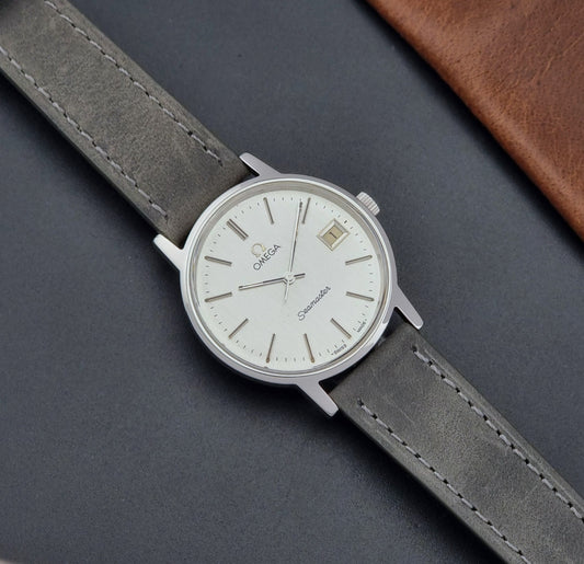 Vintage Omega Wristwatch Seamaster 136.0099 with a grey leather strap on a dark surface dial