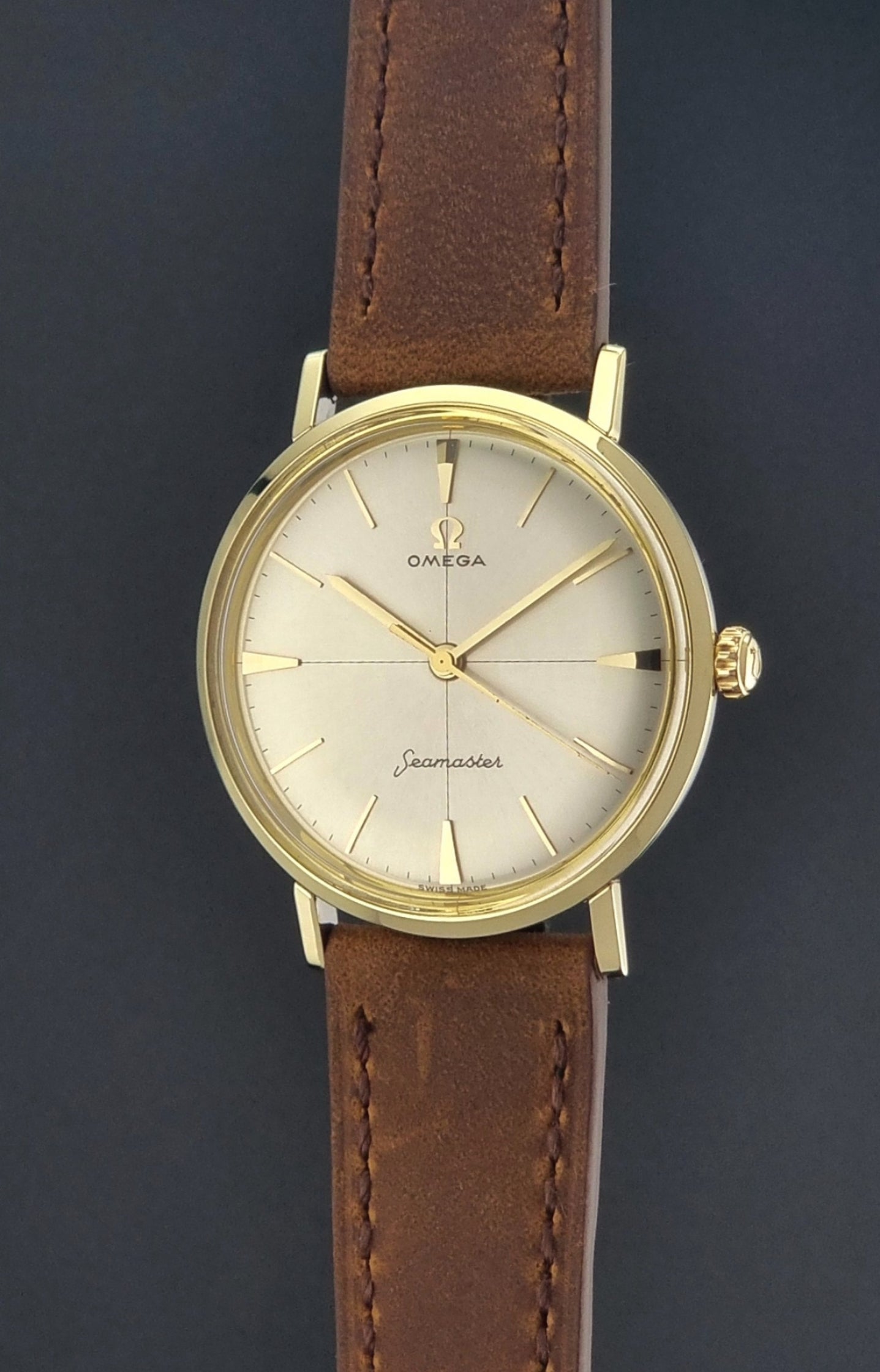 Vintage Omega Seamaster 14735 Gold watch with brown leather strap on a dark background crown view