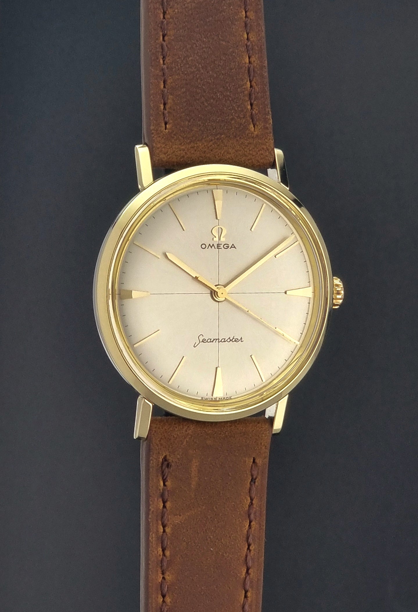 Vintage Omega Seamaster 14735 Gold watch with brown leather strap on a dark background case view