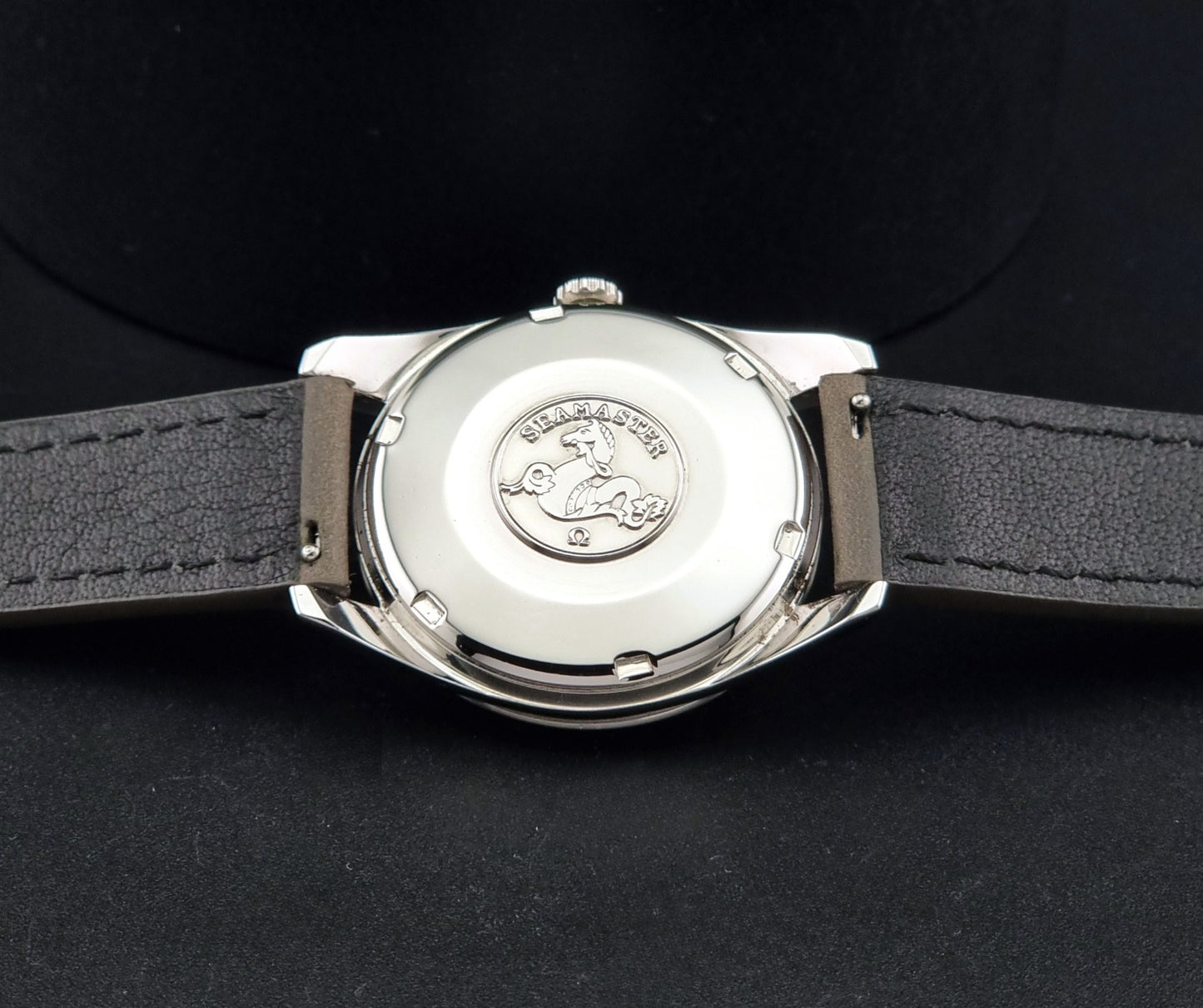 Vintage Omega Seamaster 14763 with a grey leather strap on a dark background case back view