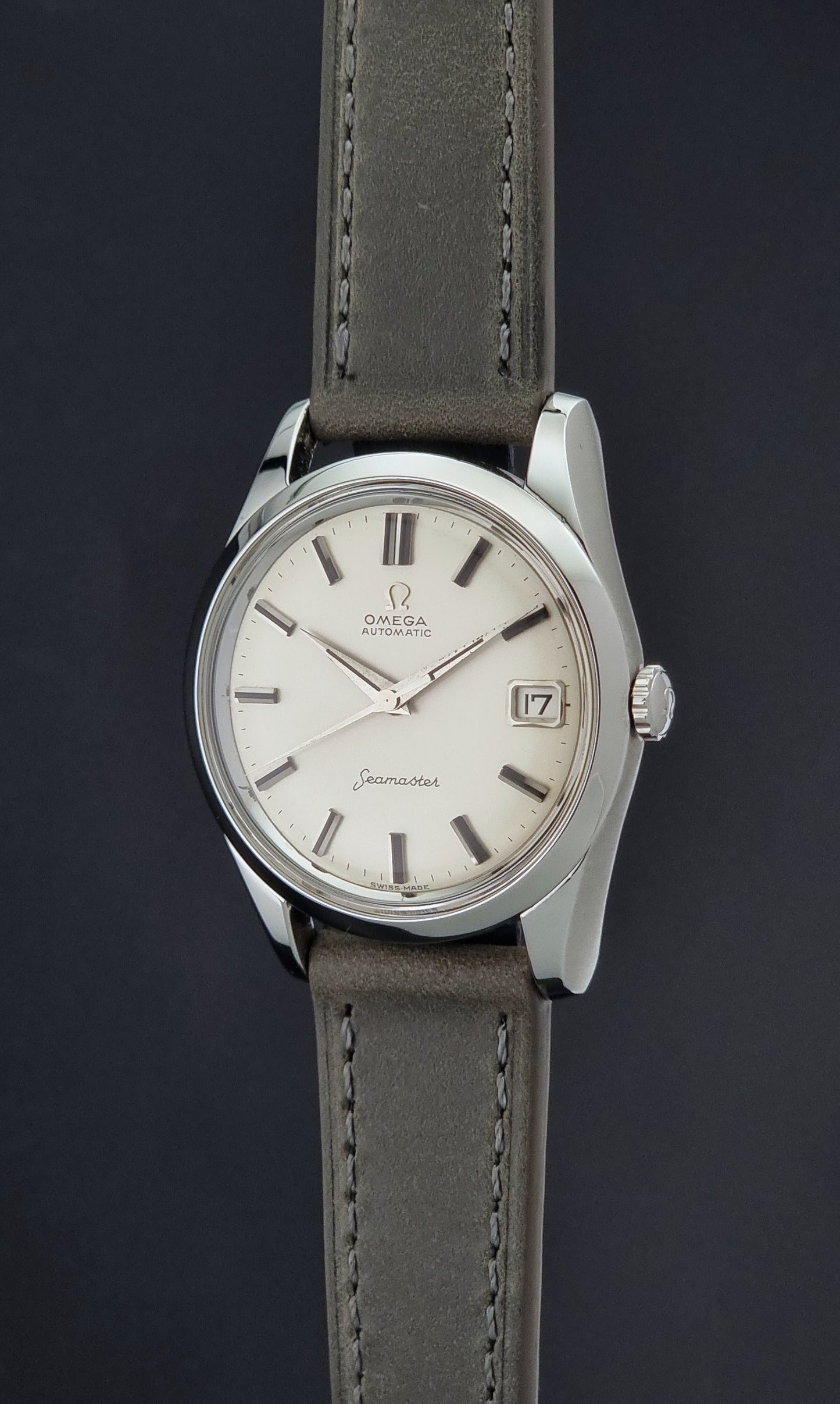 Vintage Omega Seamaster 14763 with a grey leather strap on a dark background crown profile view