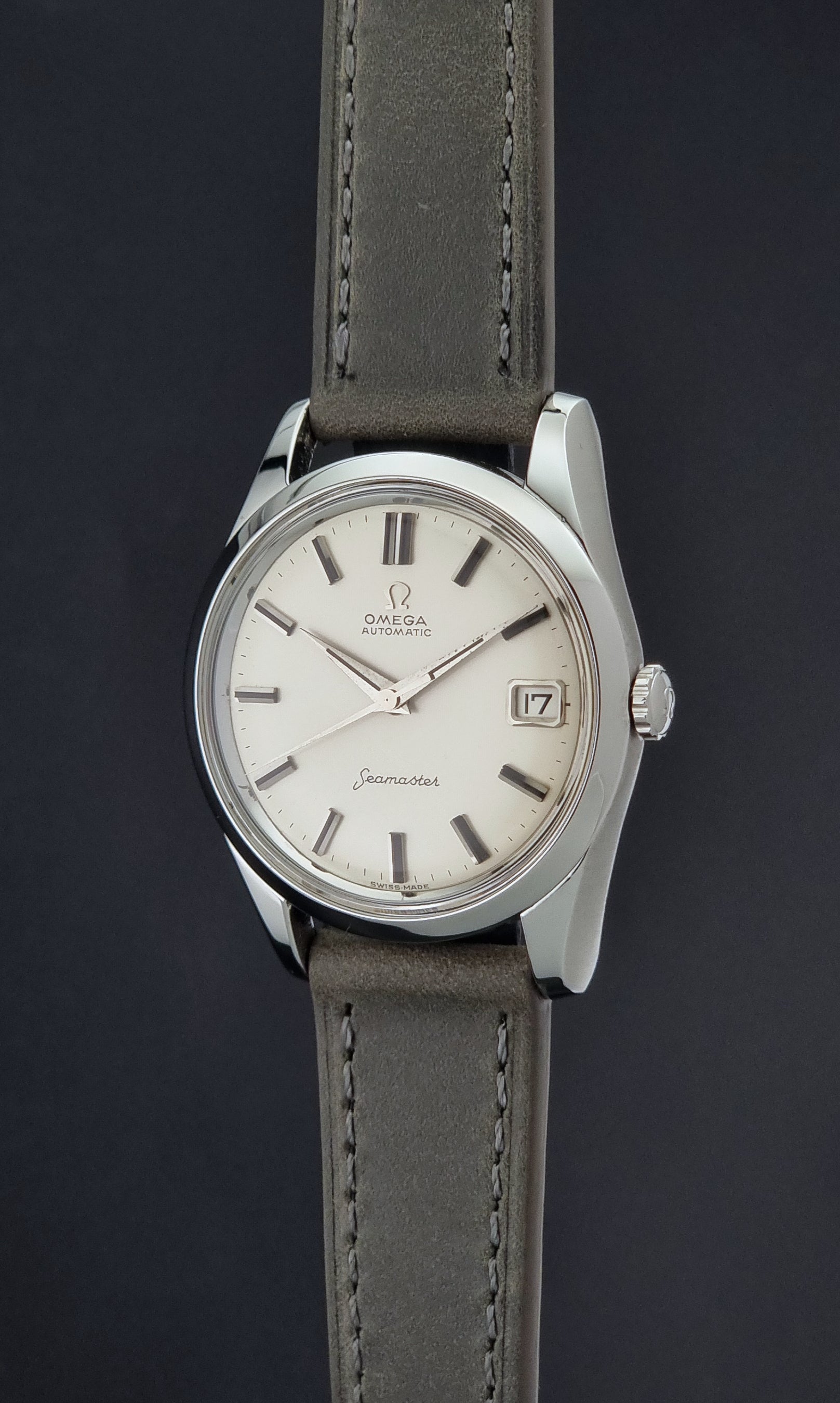 Vintage Omega Seamaster 14763 with a grey leather strap on a dark background crown profile view