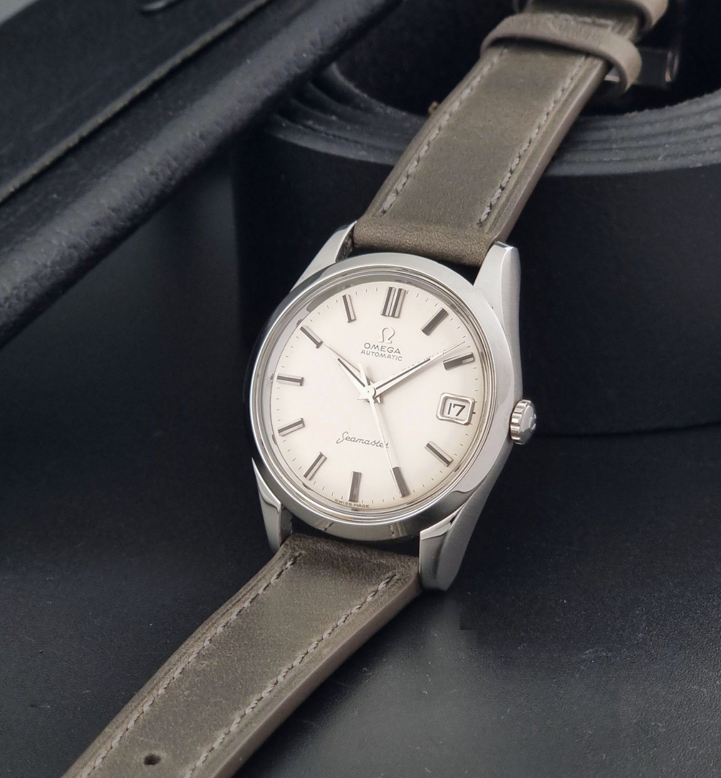 Vintage Omega Seamaster 14763 with a grey leather strap on a dark background crown view