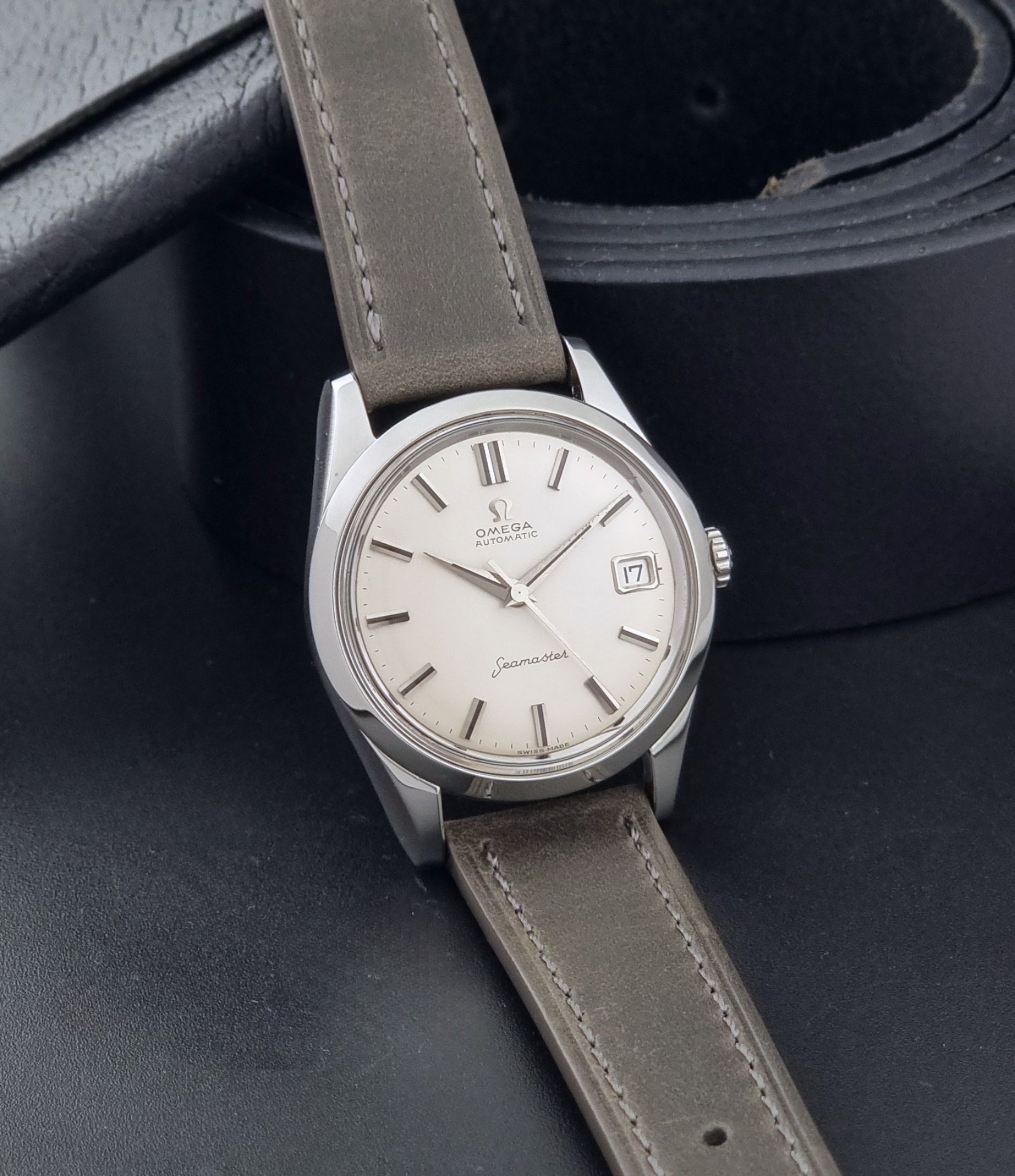 Vintage Omega Seamaster 14763 with a grey leather strap on a dark background side view