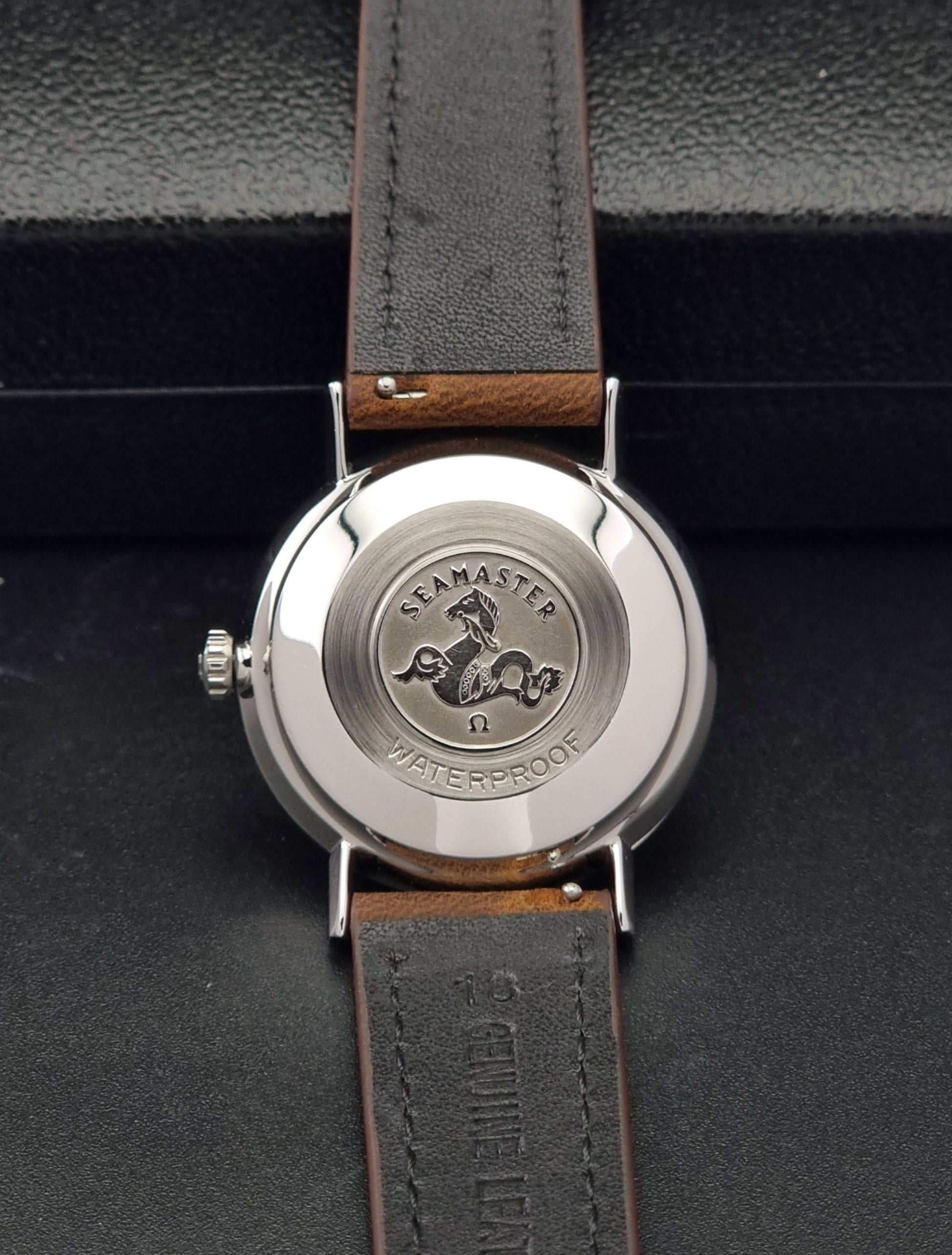 Vintage Omega Seamaster 14770 watch with a brown leather strap on a dark background case back view