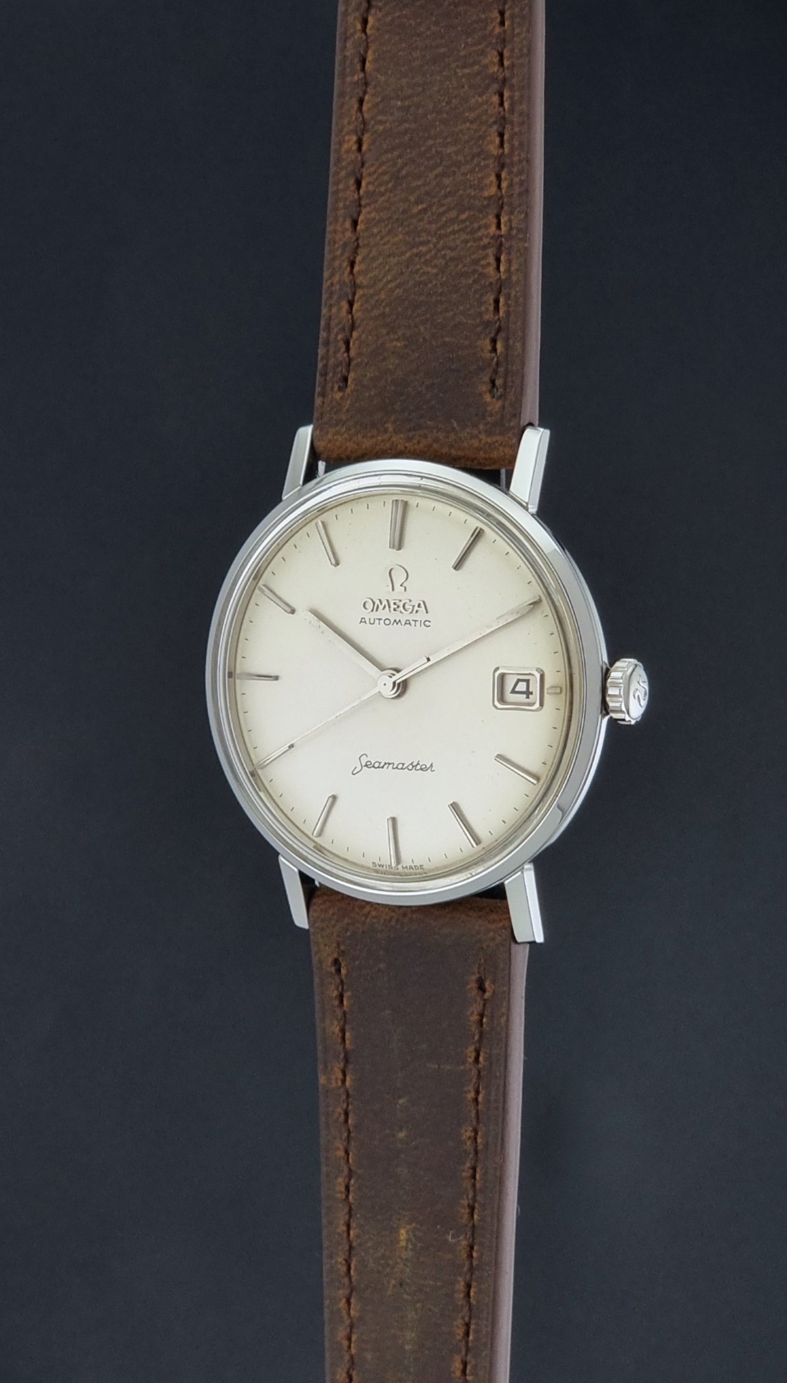 Vintage Omega Seamaster 14770 watch with a brown leather strap on a dark background crown profile view