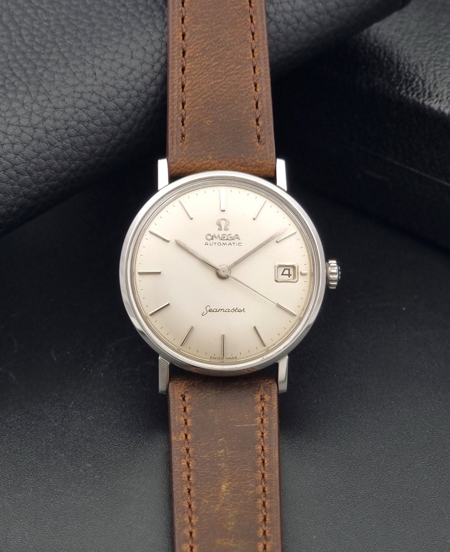 Vintage Omega Seamaster 14770 watch with a brown leather strap on a dark background dial view