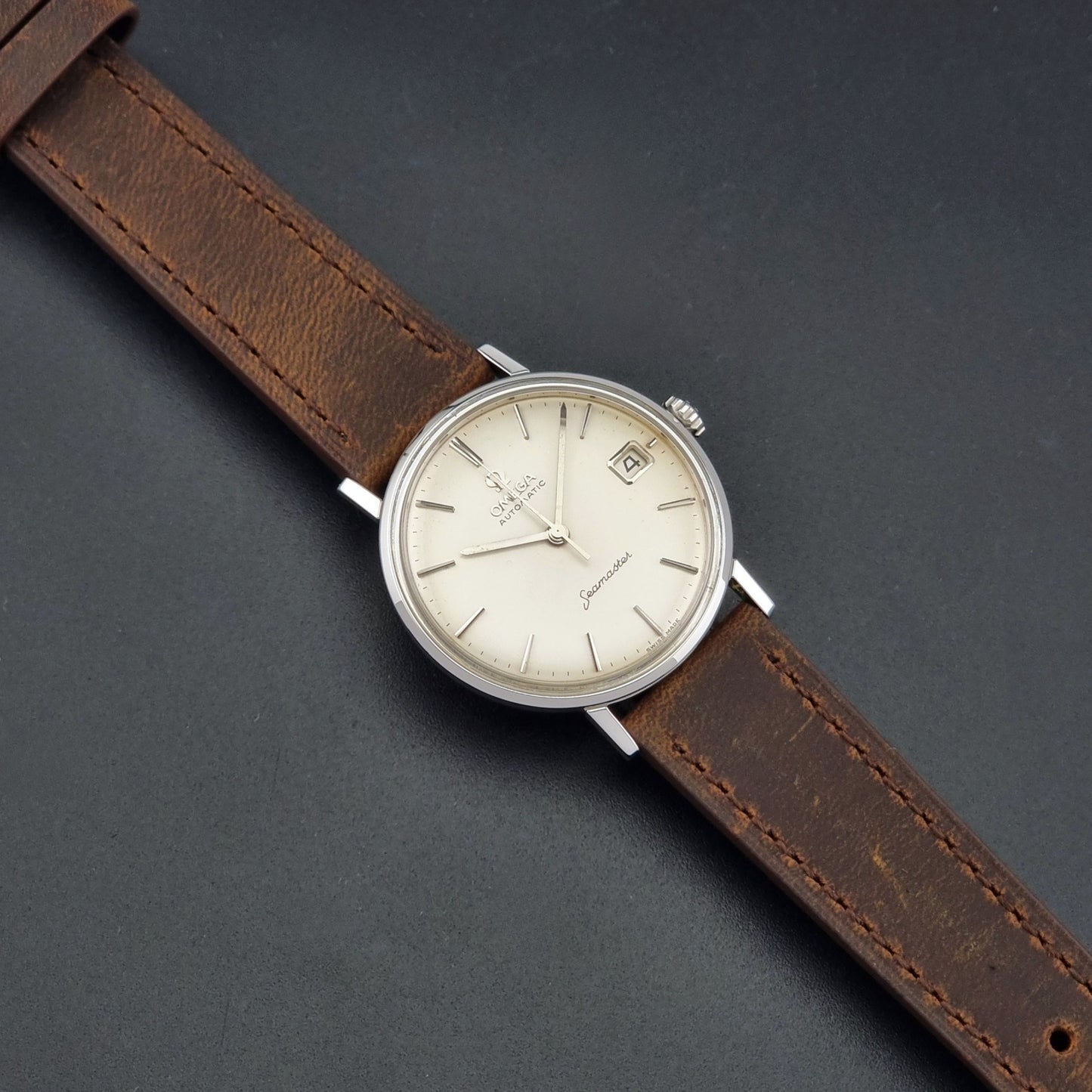 Vintage Omega Seamaster 14770 watch with a brown leather strap on a dark background dial