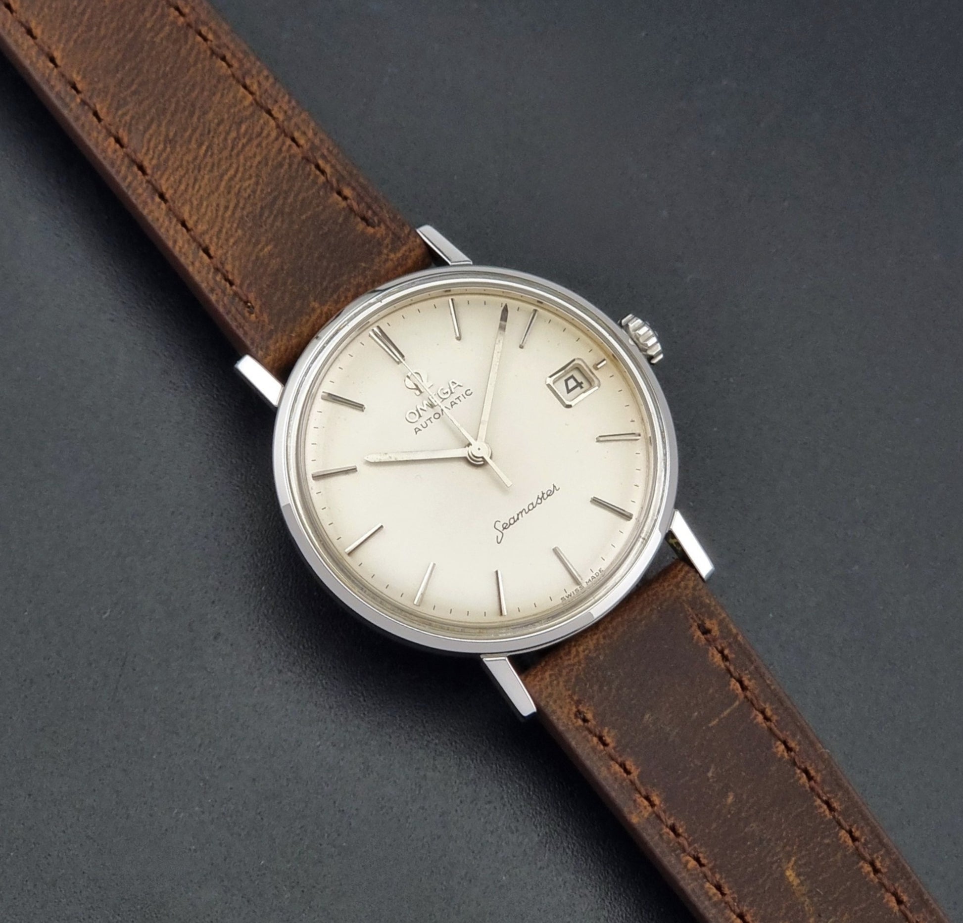 Vintage Omega Seamaster 14770 watch with a brown leather strap on a dark background close up dial view