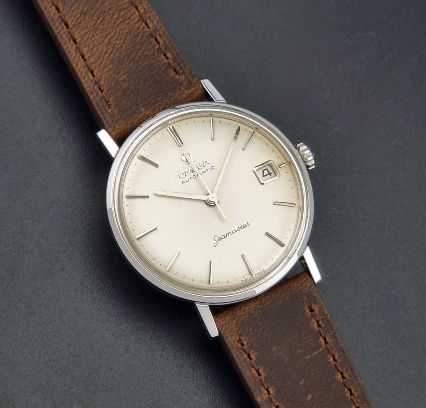 Vintage Omega Seamaster 14770 watch with a brown leather strap on a dark background front view