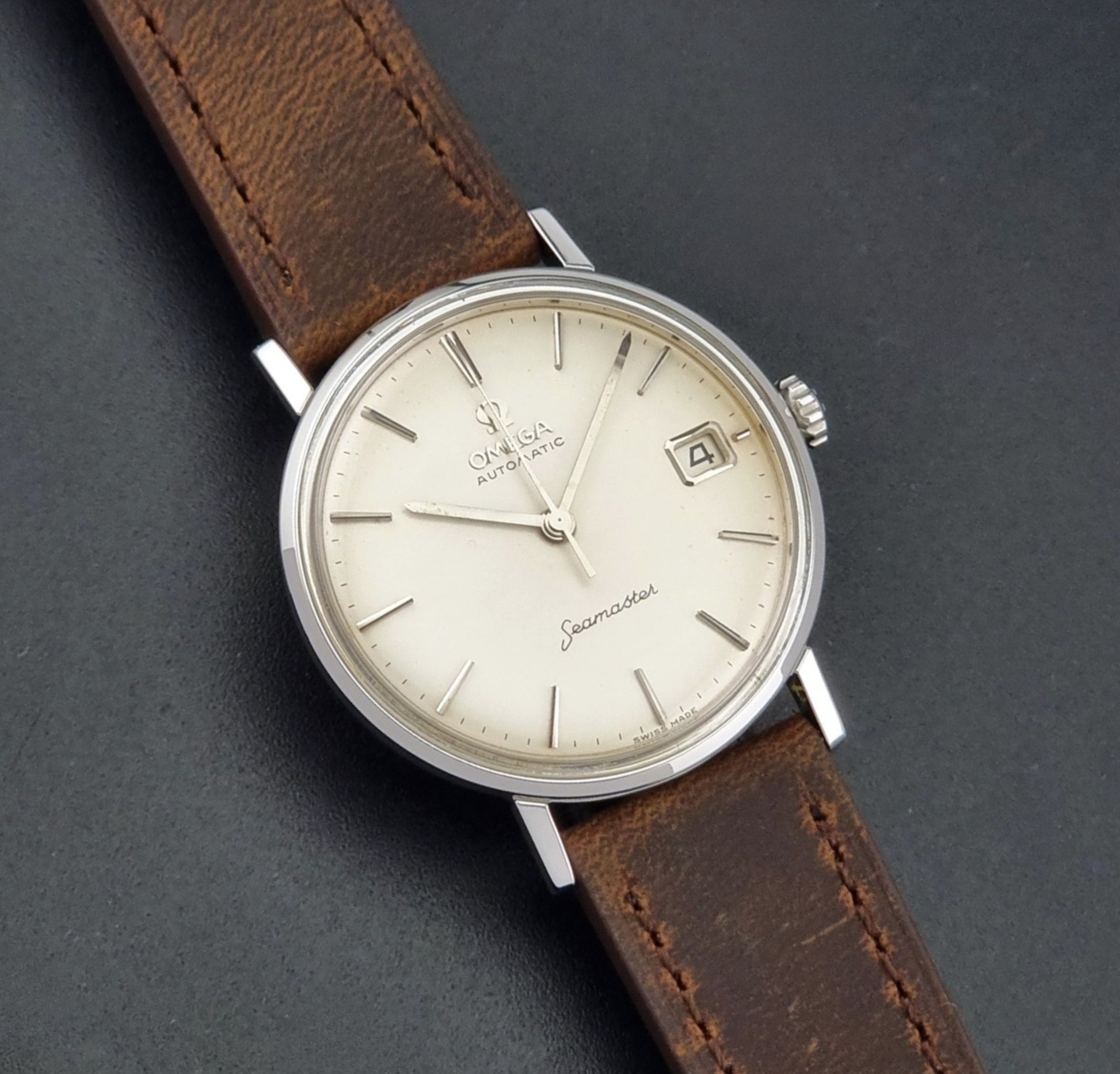 Vintage Omega Seamaster 14770 watch with a brown leather strap on a dark background front view