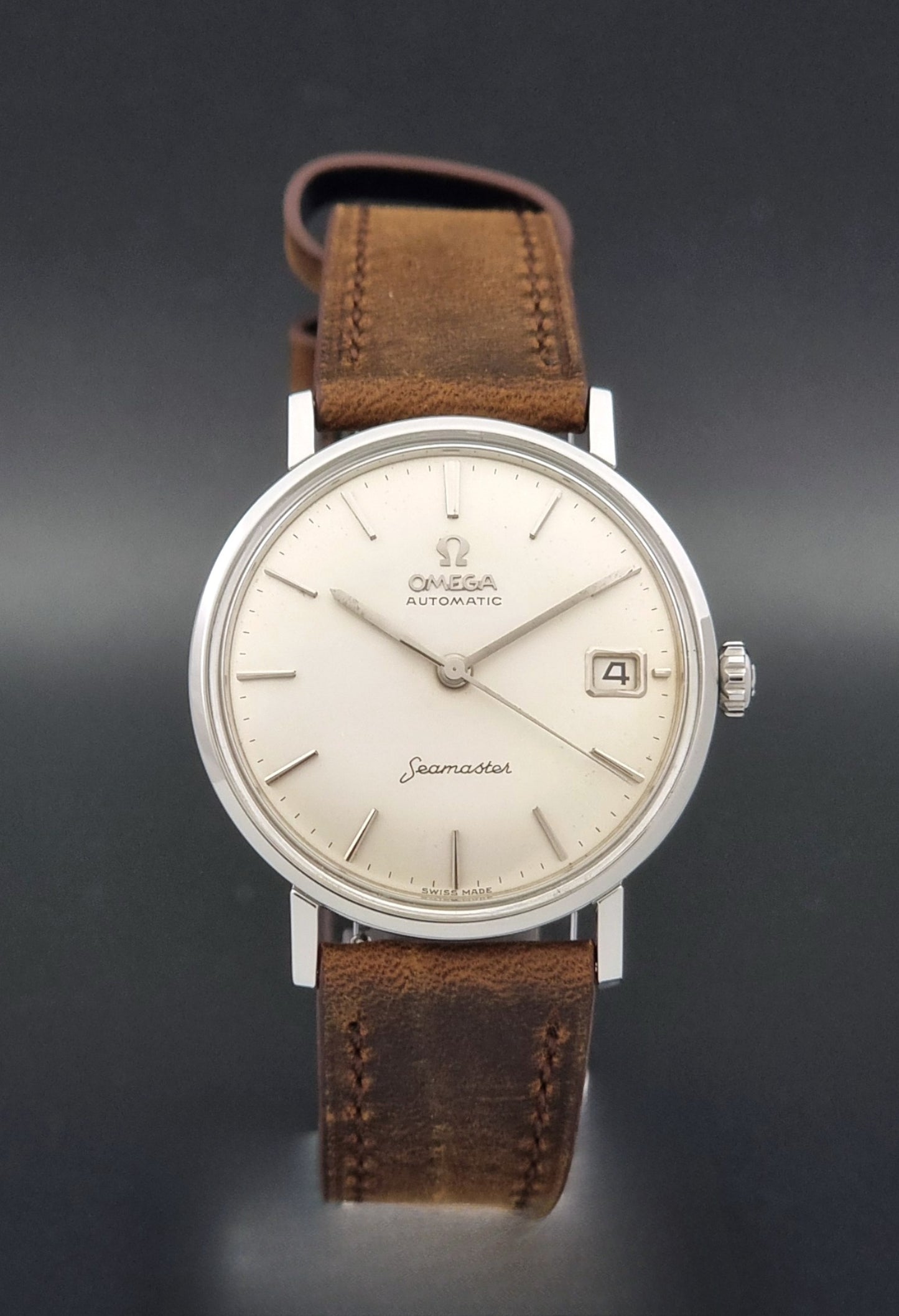 Vintage Omega Seamaster 14770 watch with a brown leather strap on a dark background close dial view