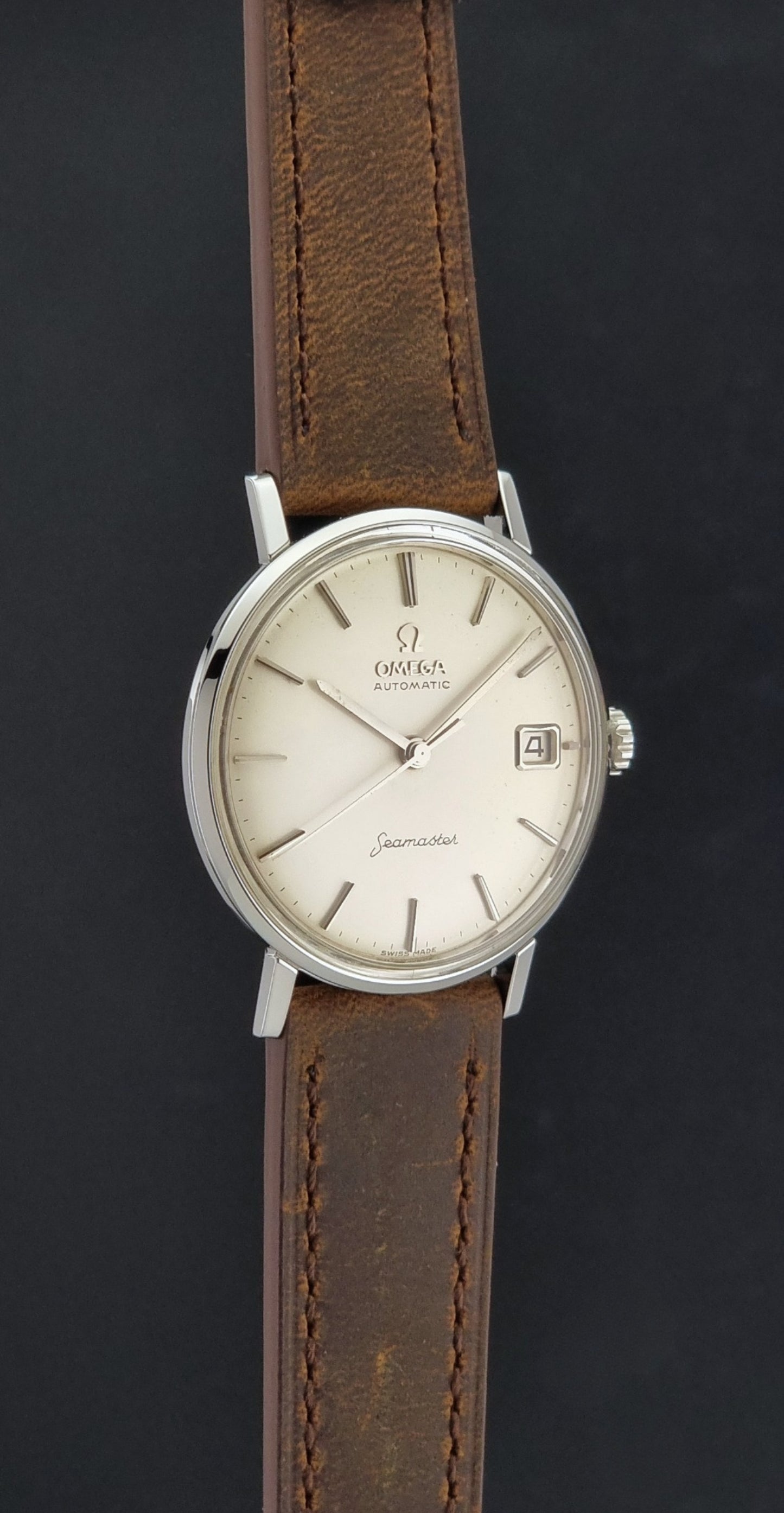 Vintage Omega Seamaster 14770 watch with a brown leather strap on a dark background side profile view