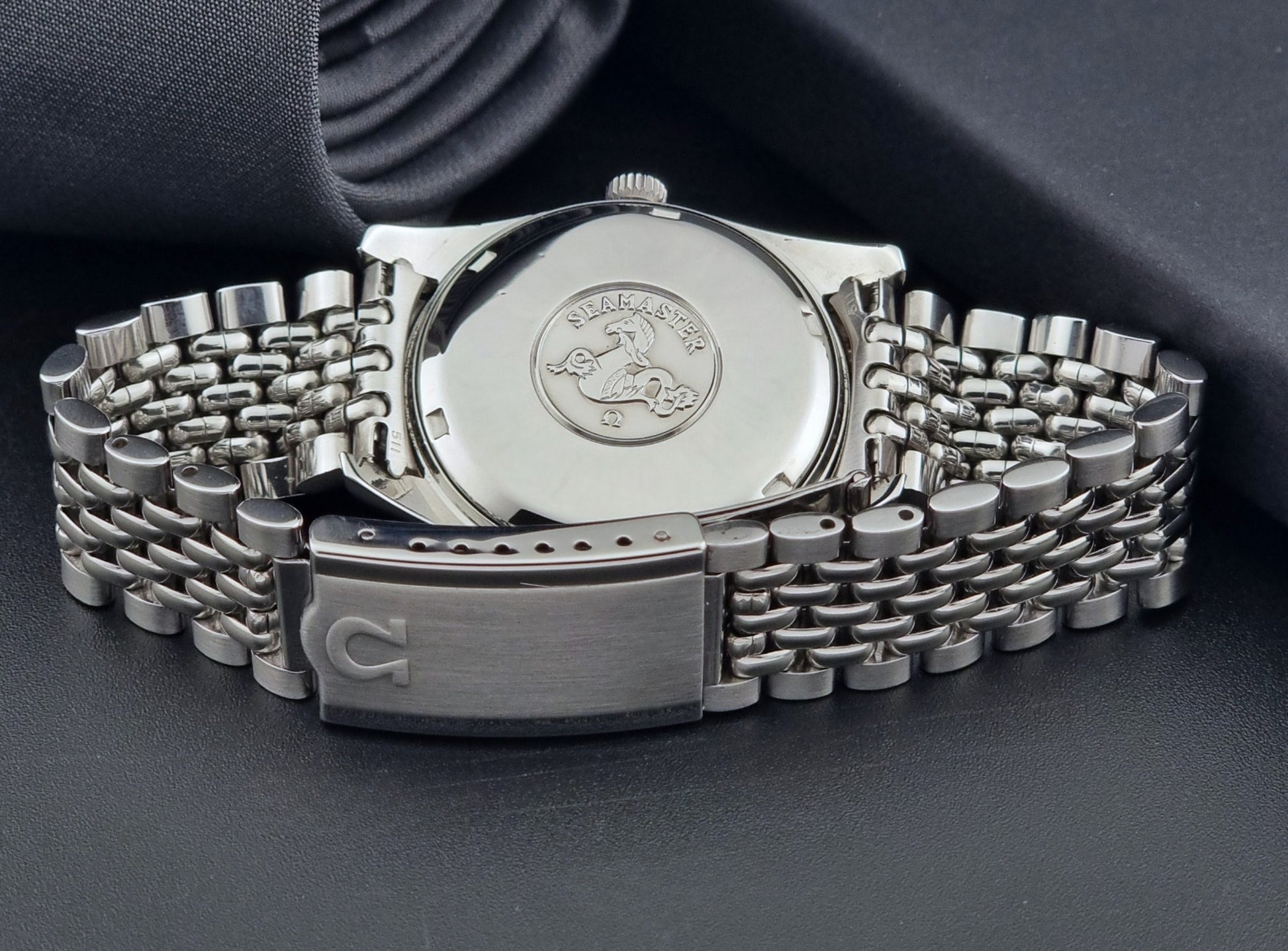 Vintage Omega Wristwatch Seamaster 166.010 Chronometer with stainless steel bracelet on a dark background bracelet view