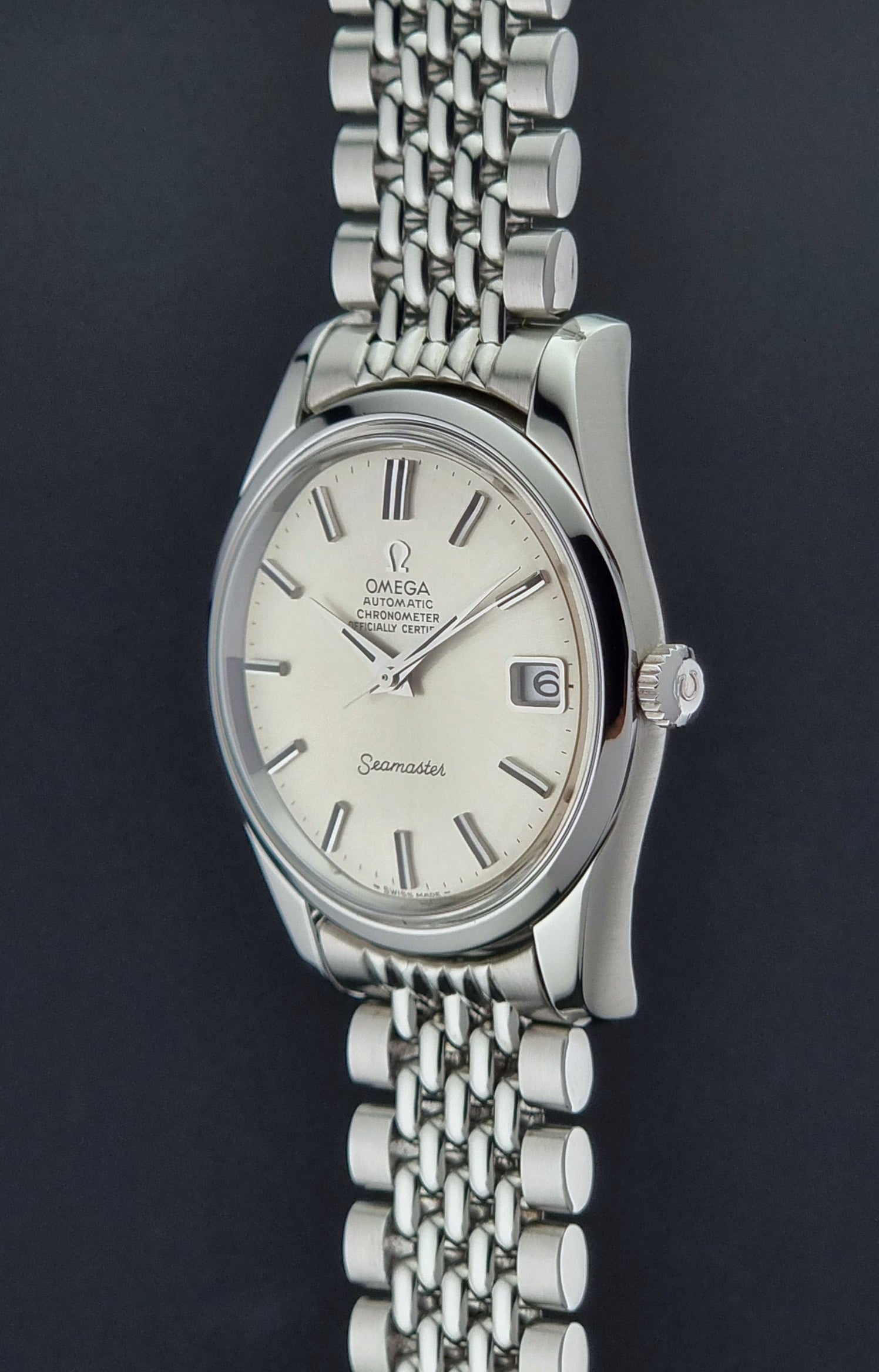 Vintage Omega Wristwatch Seamaster 166.010 Chronometer with stainless steel bracelet on a dark background crown profile view