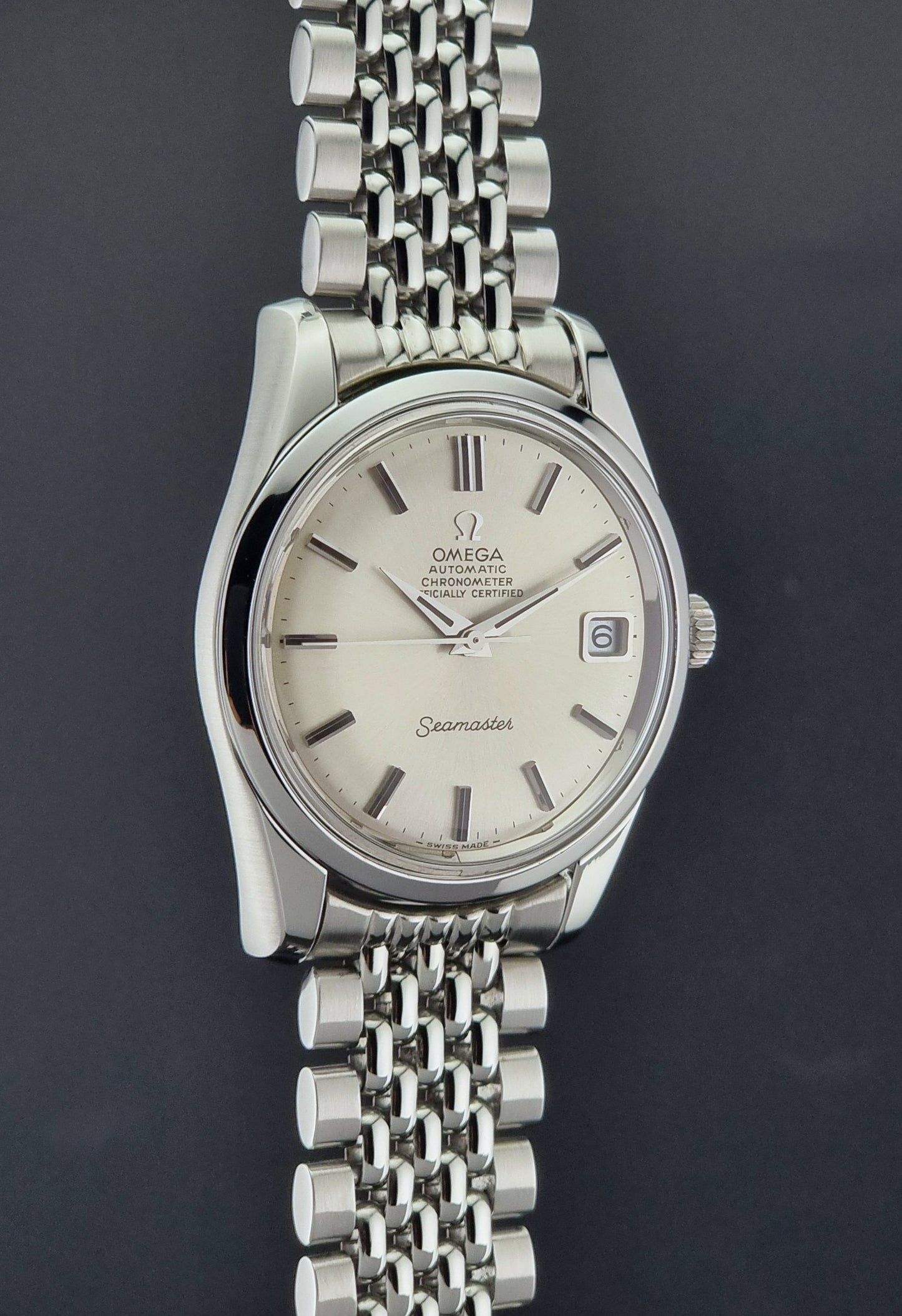 Vintage Omega Wristwatch Seamaster 166.010 Chronometer with stainless steel bracelet on a dark background close side profile view