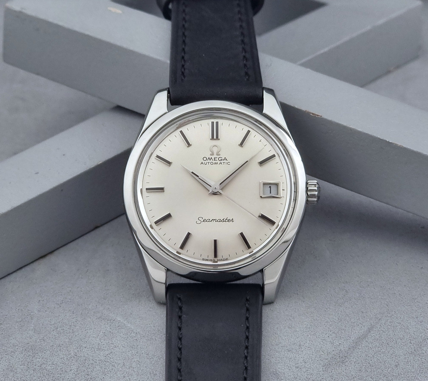 Vintage Omega Wristwatch Seamaster 166.010 with black leather strap on a gray background dial view