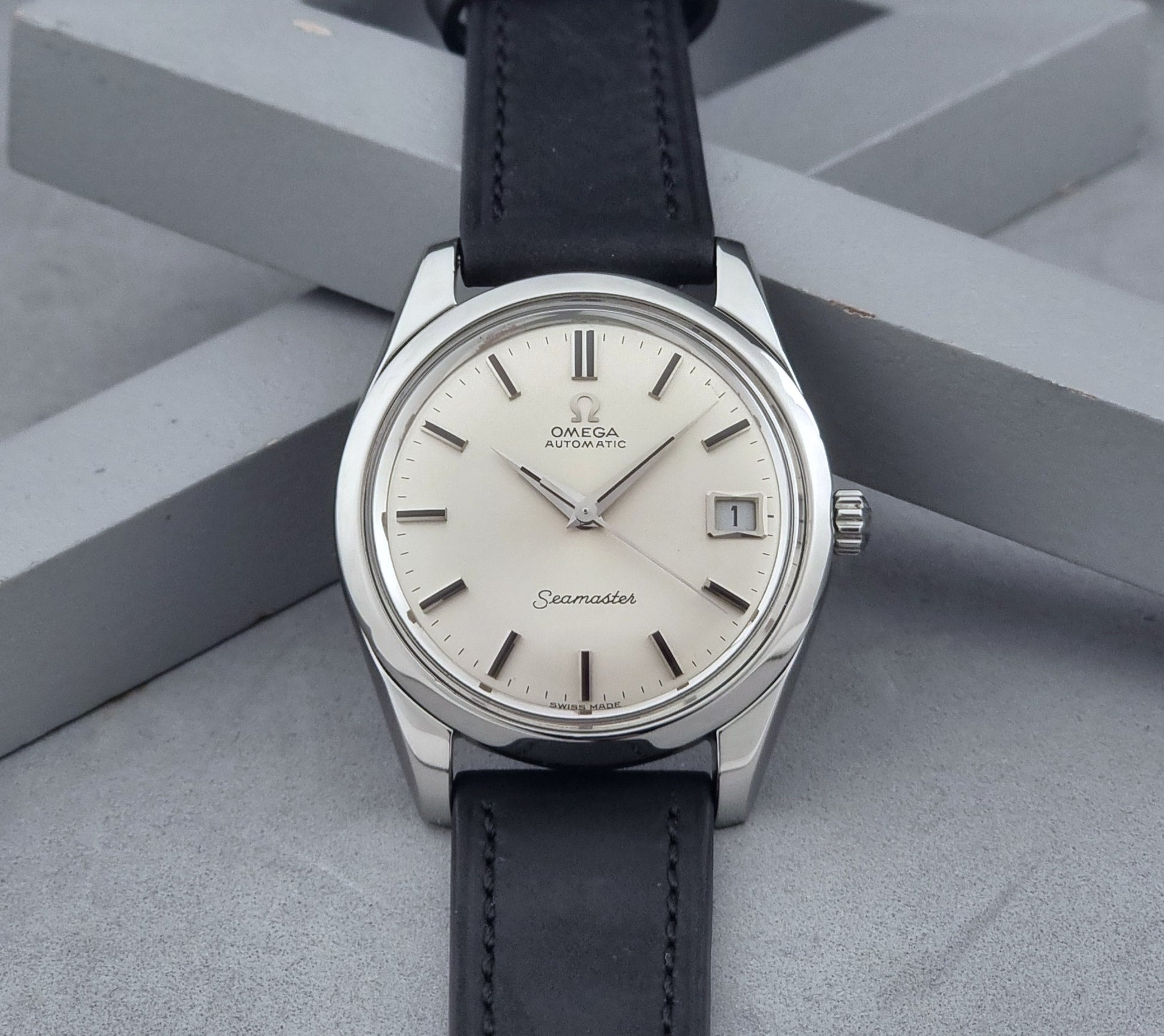 Vintage Omega Wristwatch Seamaster 166.010 with black leather strap on a gray background dial view