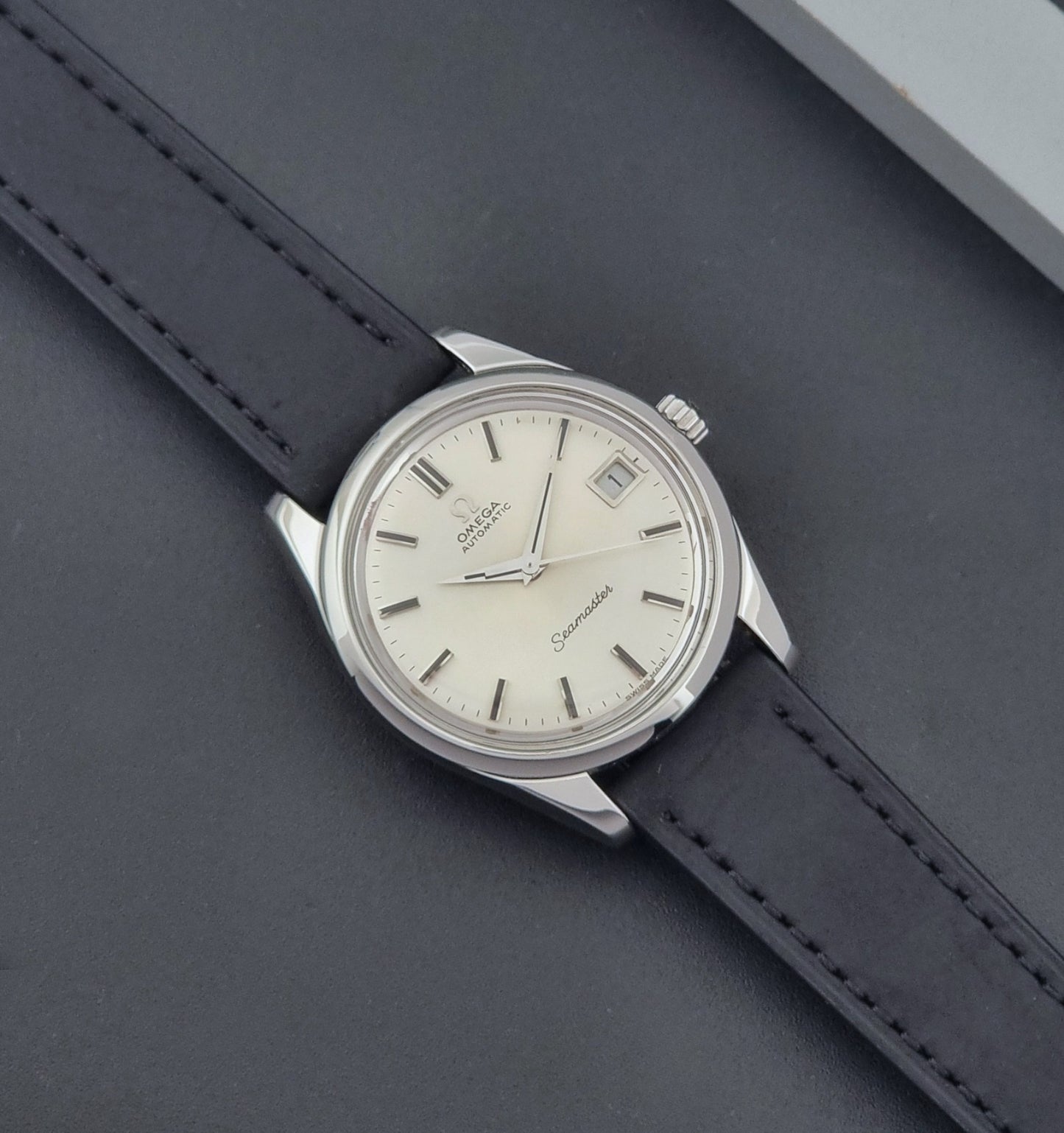 Vintage Omega Wristwatch Seamaster 166.010 with black leather strap on a gray background dial