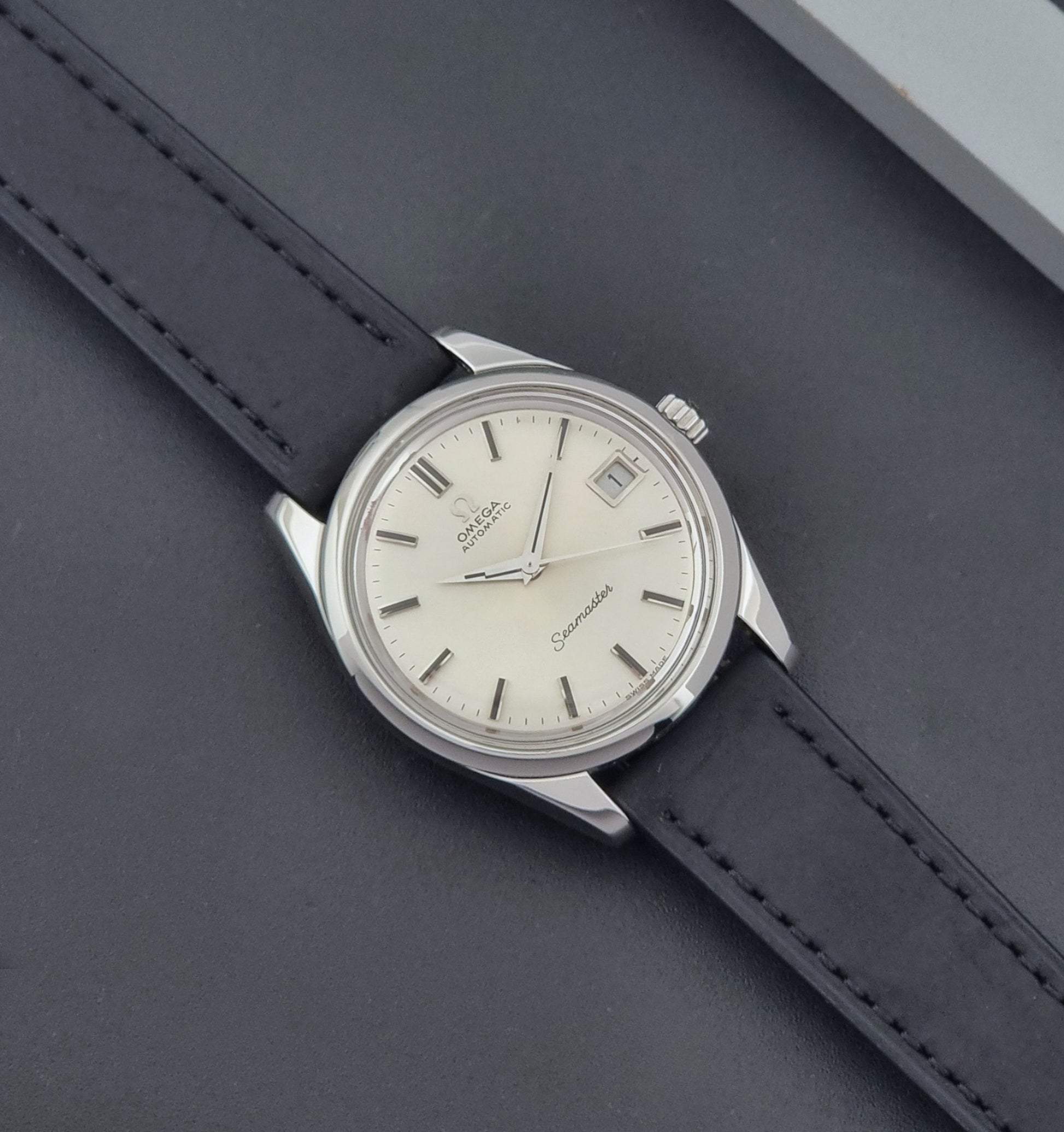 Vintage Omega Wristwatch Seamaster 166.010 with black leather strap on a gray background dial