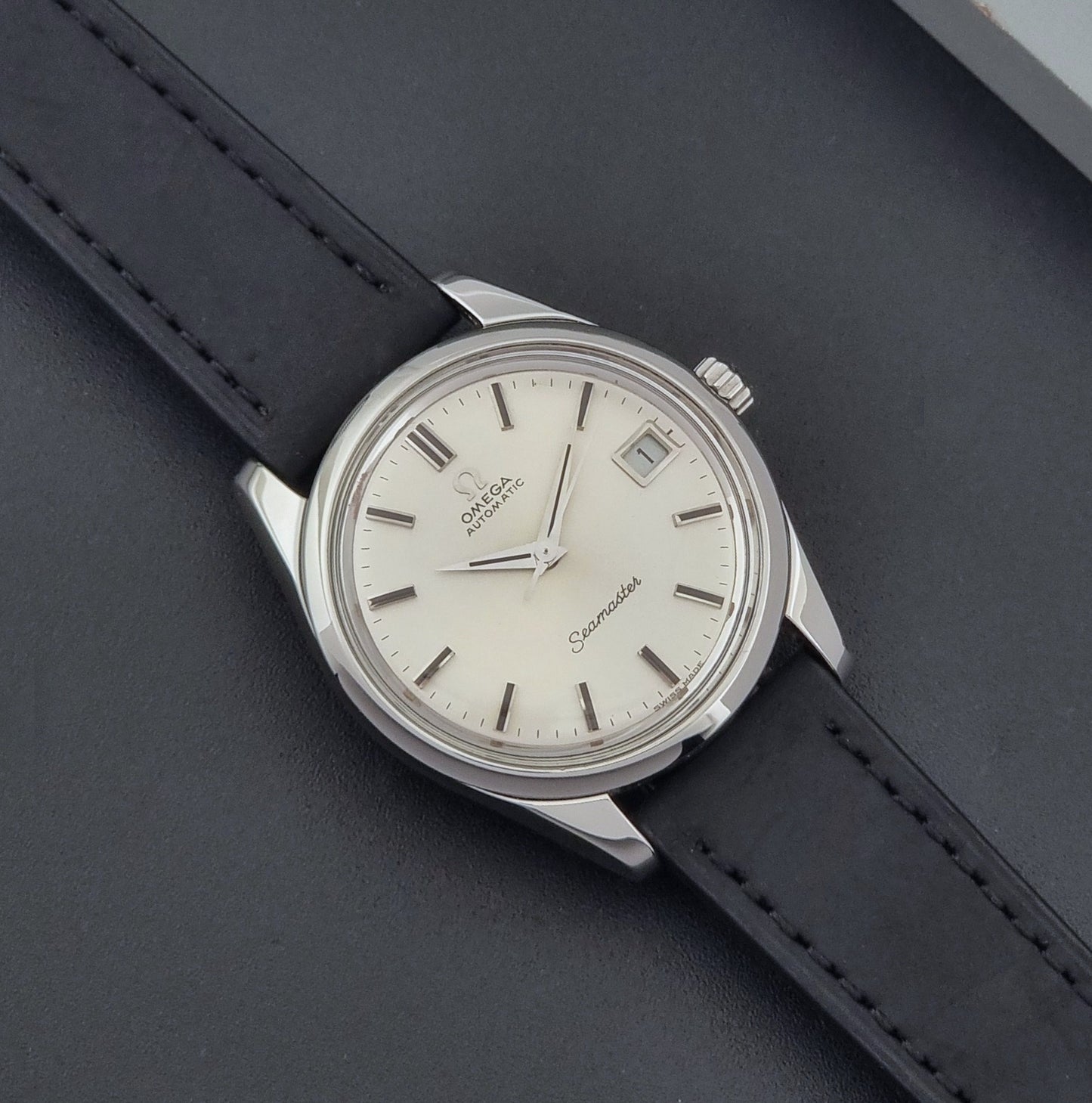 Vintage Omega Wristwatch Seamaster 166.010 with black leather strap on a gray background close up dial view
