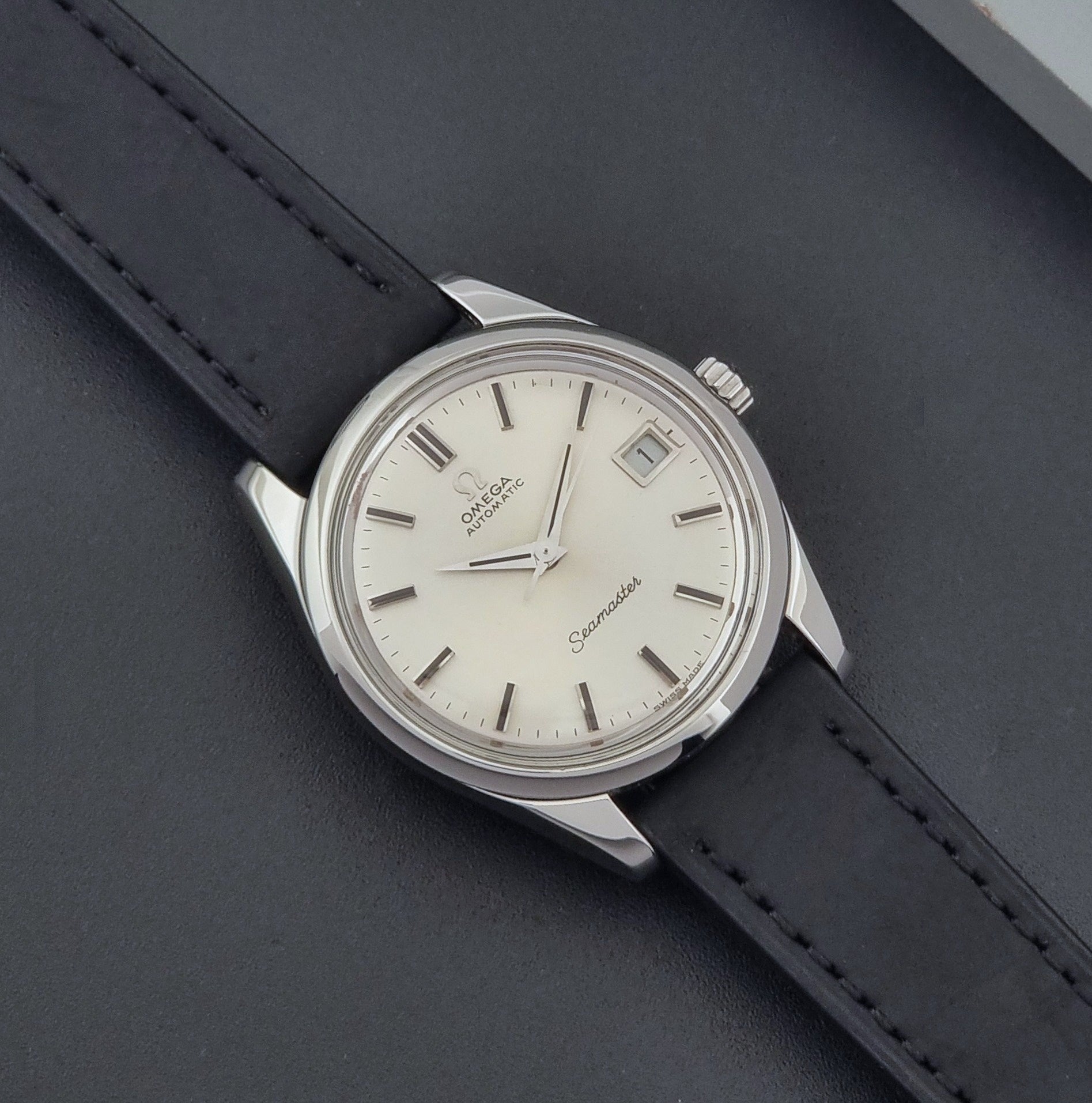 Vintage Omega Wristwatch Seamaster 166.010 with black leather strap on a gray background close up dial view