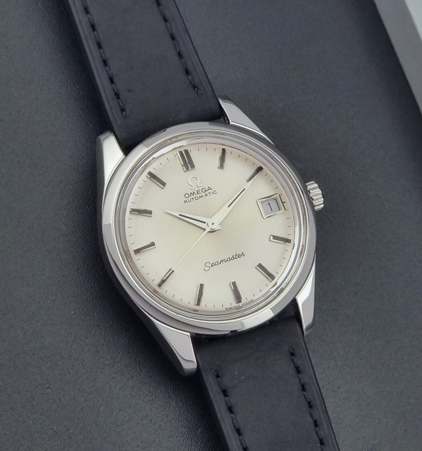 Vintage Omega Wristwatch Seamaster 166.010 with black leather strap on a gray background front view