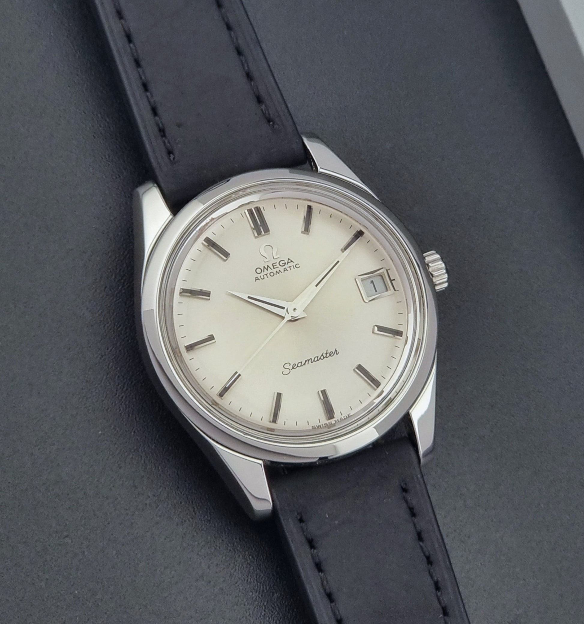 Vintage Omega Wristwatch Seamaster 166.010 with black leather strap on a gray background front view