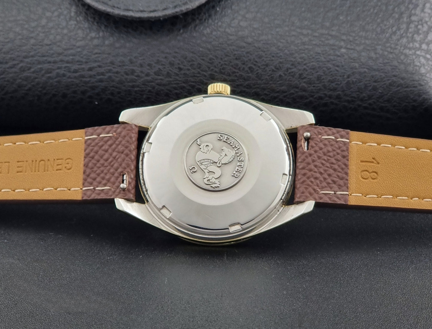 Vintage Omega Wristwatch Seamaster 14763  with a brown leather strap on a dark textured background case back view