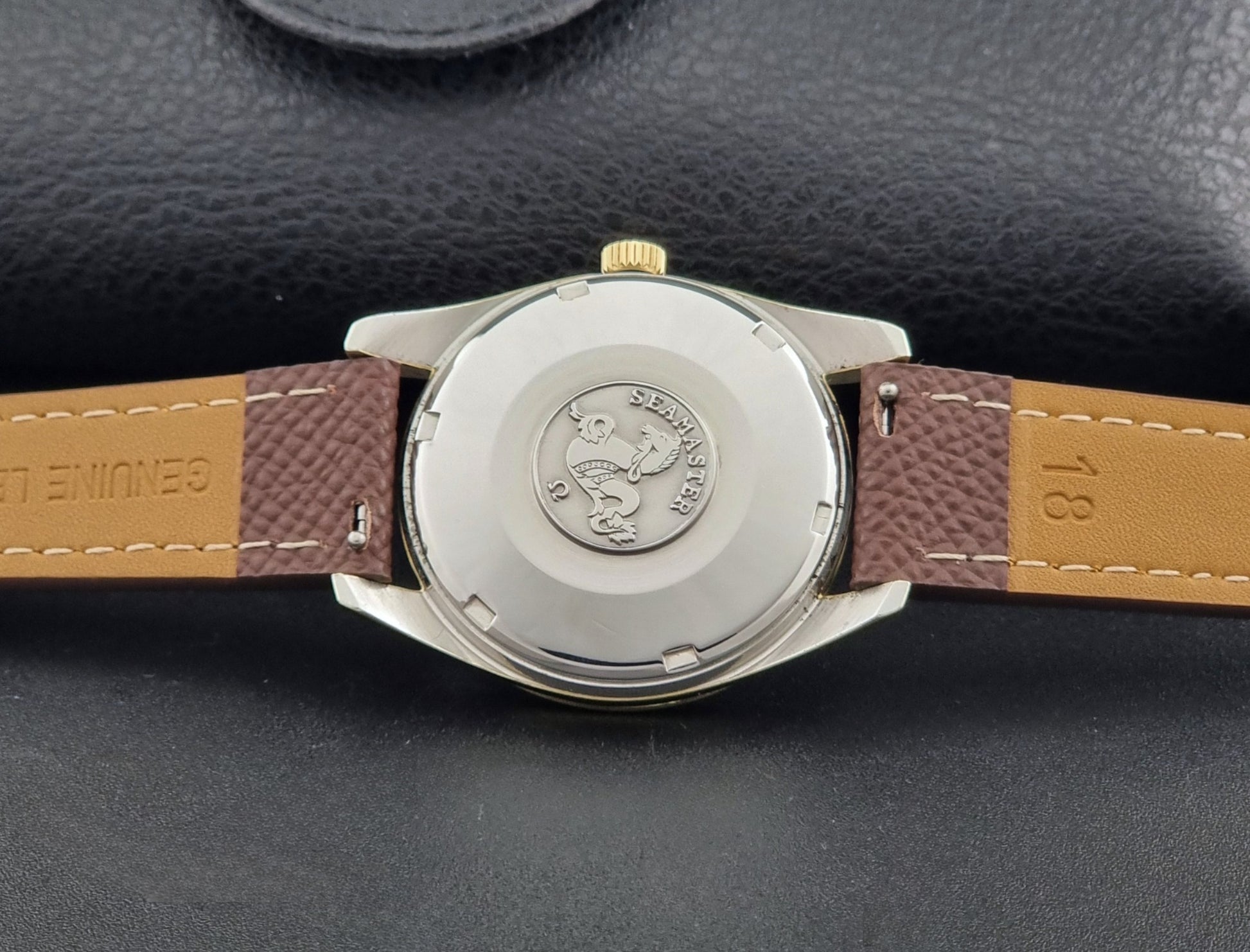 Vintage Omega Wristwatch Seamaster 14763  with a brown leather strap on a dark textured background case back view