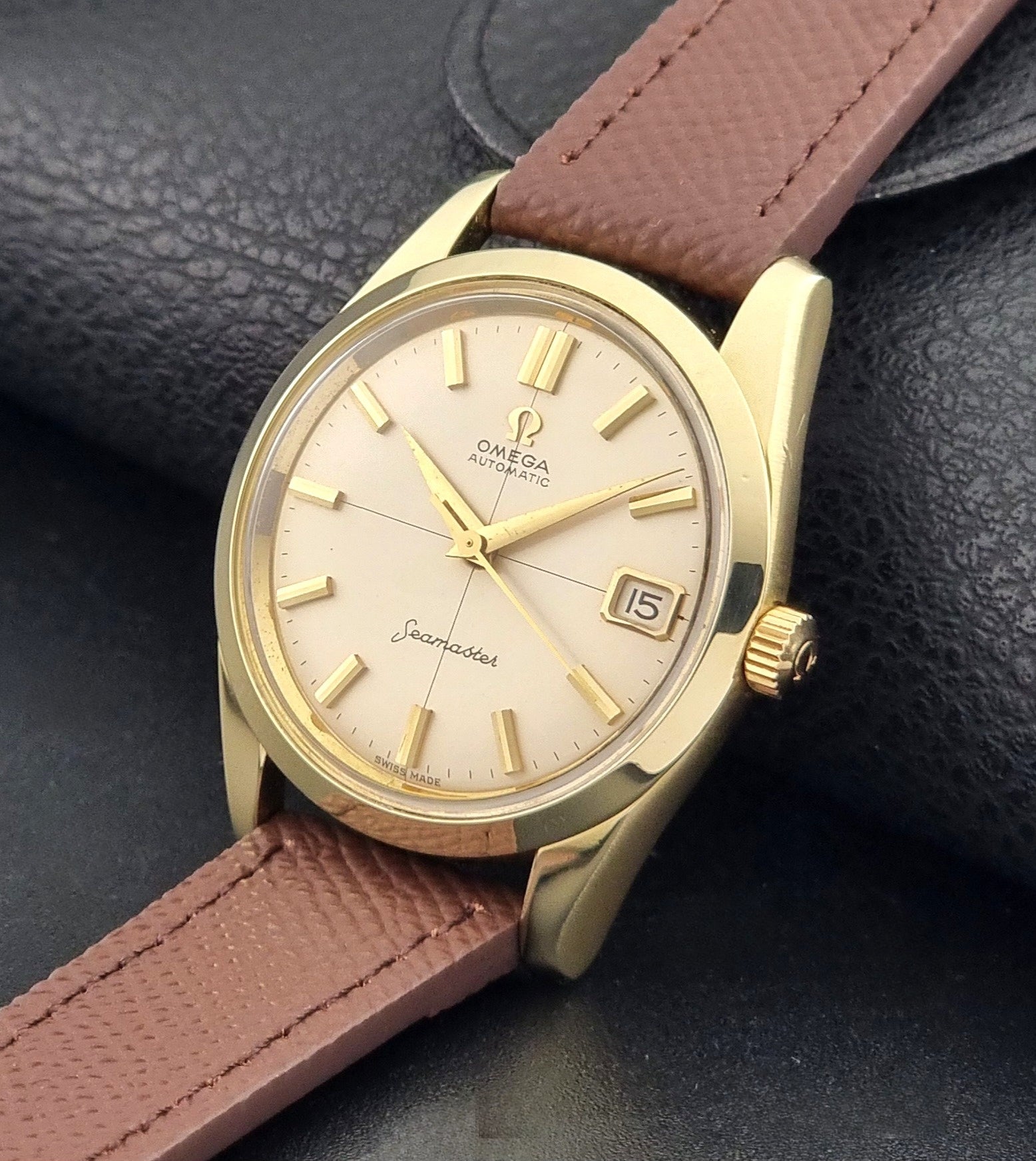 Vintage Omega Wristwatch Seamaster 14763  with a brown leather strap on a dark textured background crown view