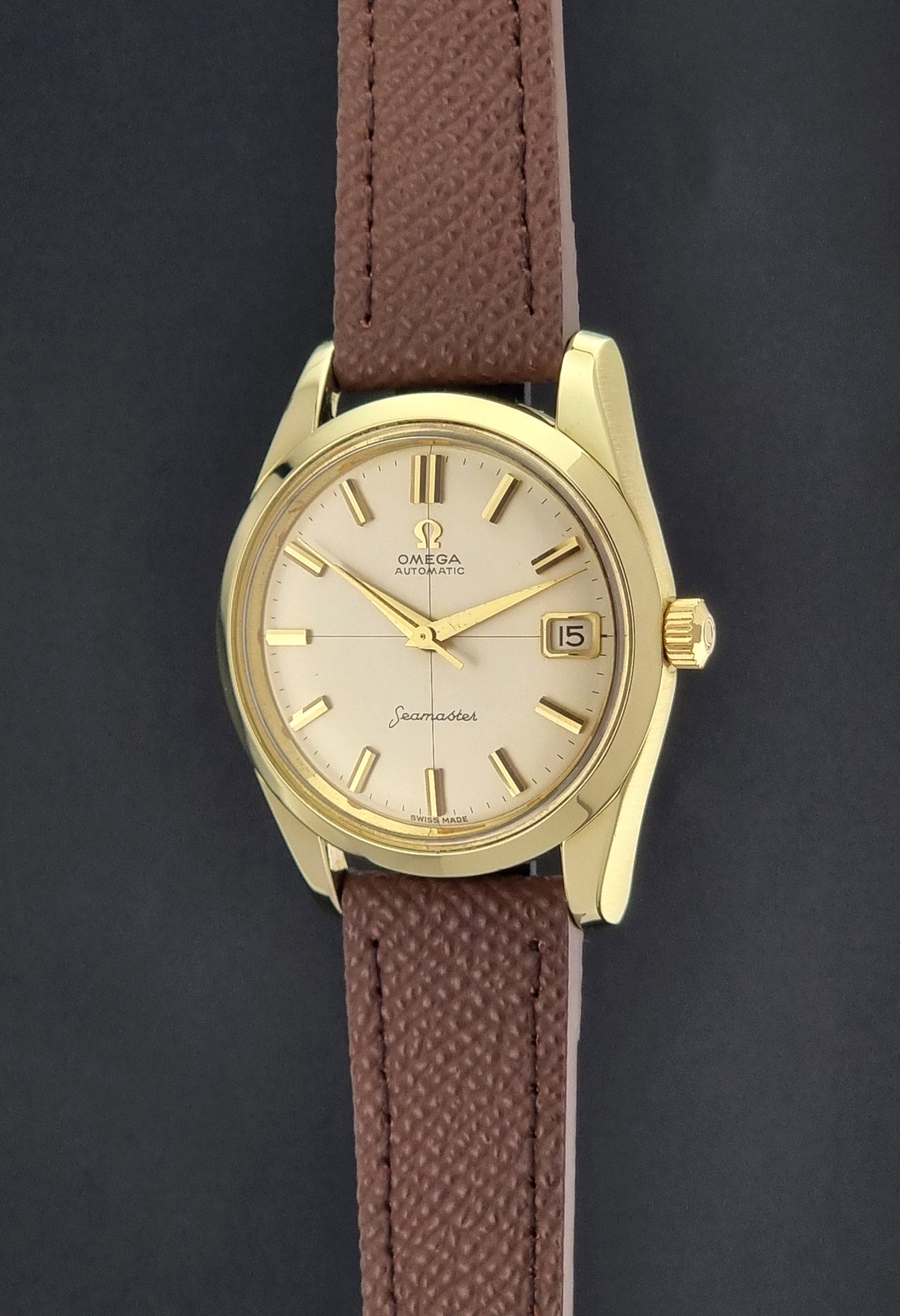 Vintage Omega Wristwatch Seamaster 14763  with a brown leather strap on a dark textured background crown profile view