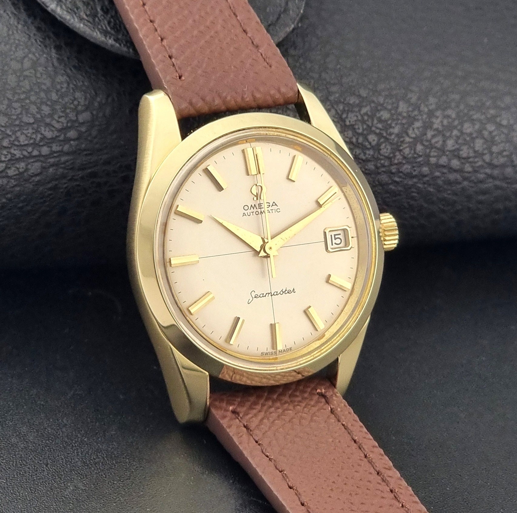 Vintage Omega Wristwatch Seamaster 14763  with a brown leather strap on a dark textured background side view