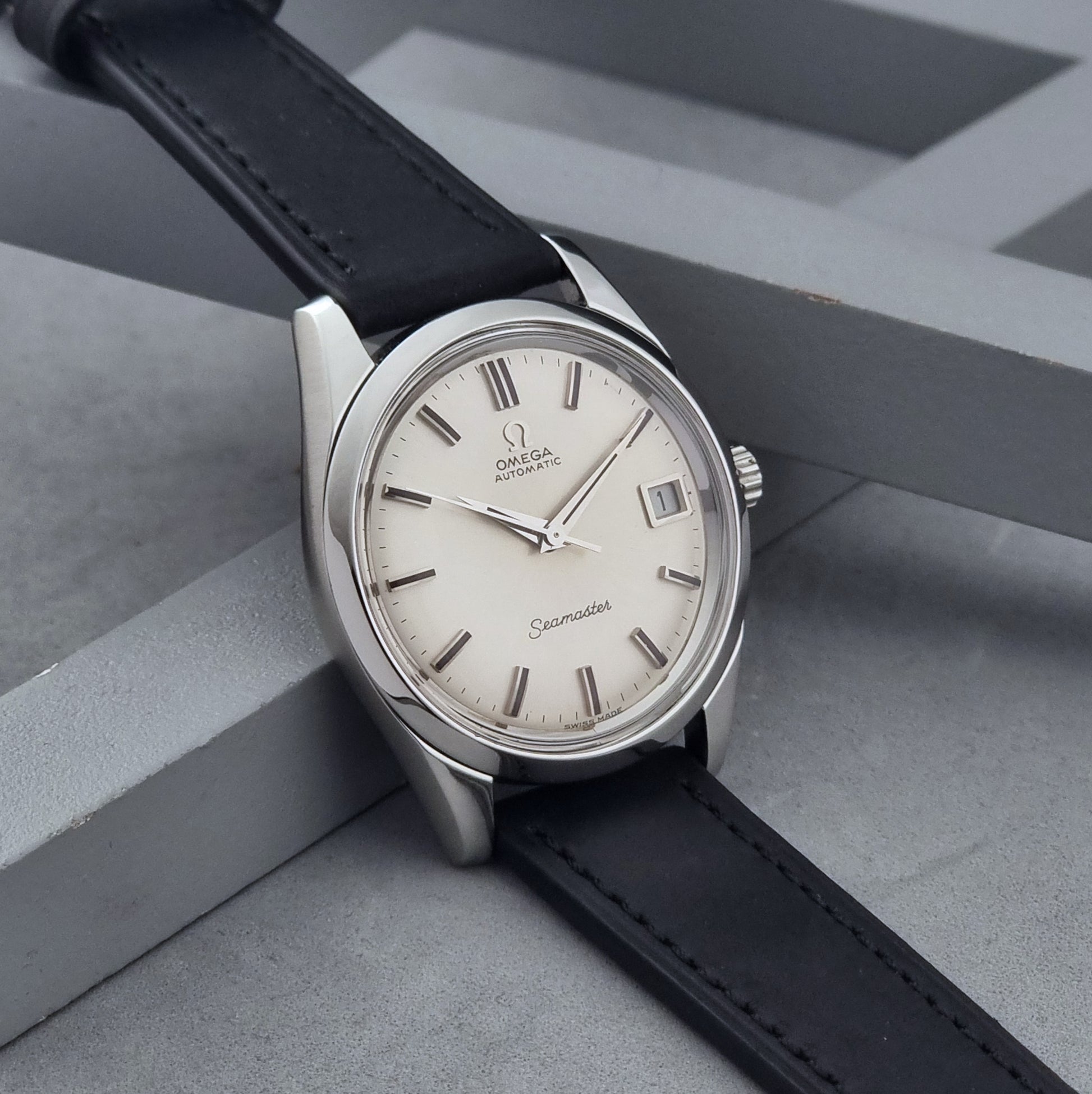 Vintage Omega Wristwatch Seamaster 166.010 with black leather strap on a gray background side view