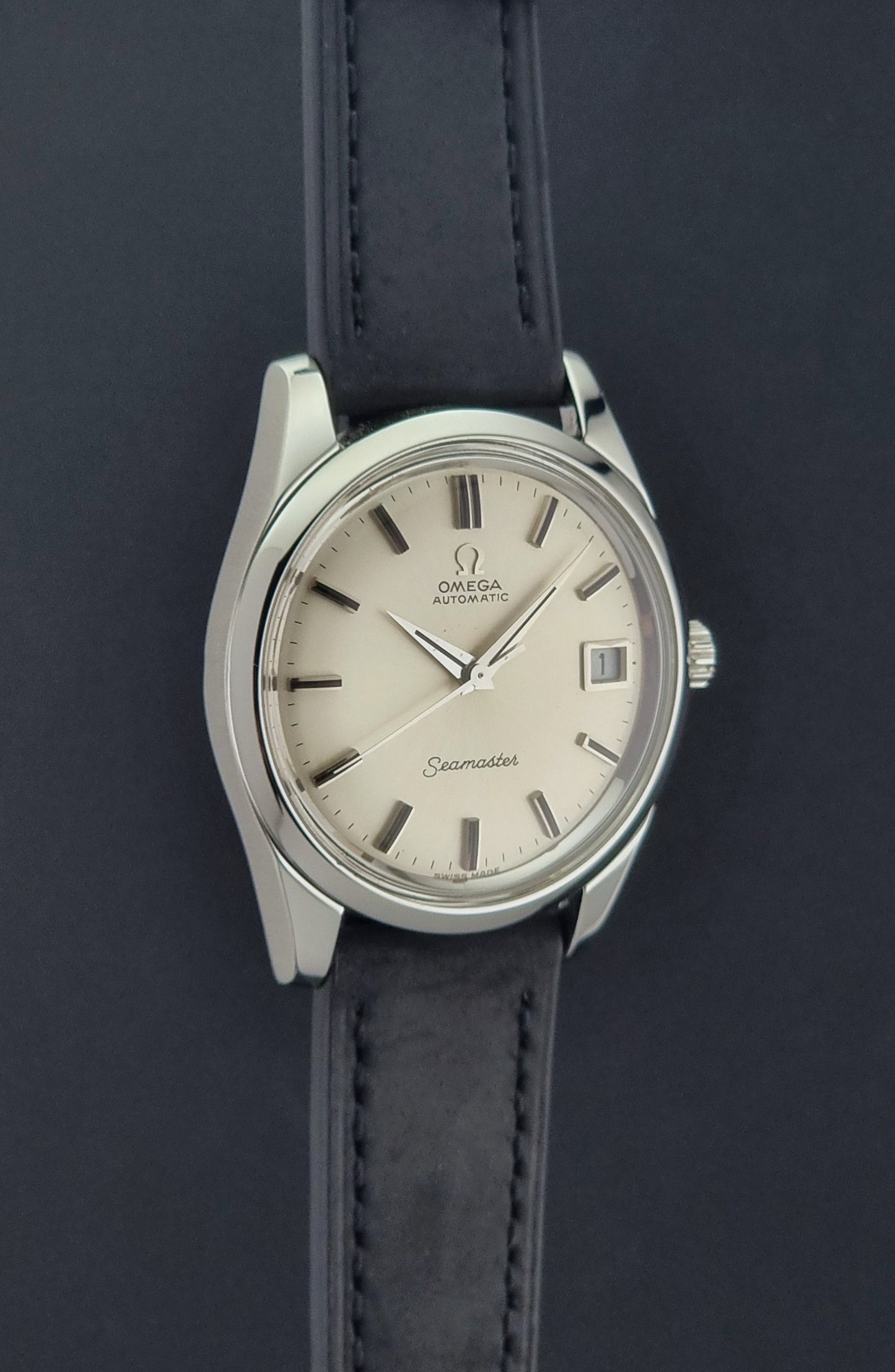 Vintage Omega Wristwatch Seamaster 166.010 with black leather strap on a gray background side profile view