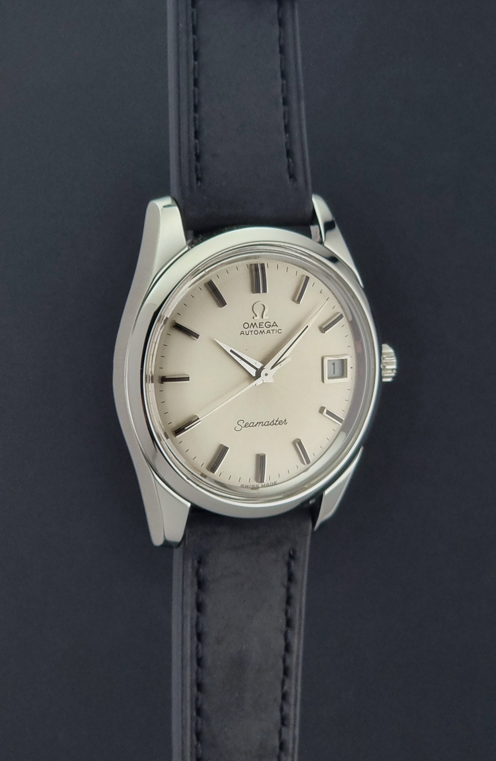 Vintage Omega Wristwatch Seamaster 166.010 with black leather strap on a gray background side profile view