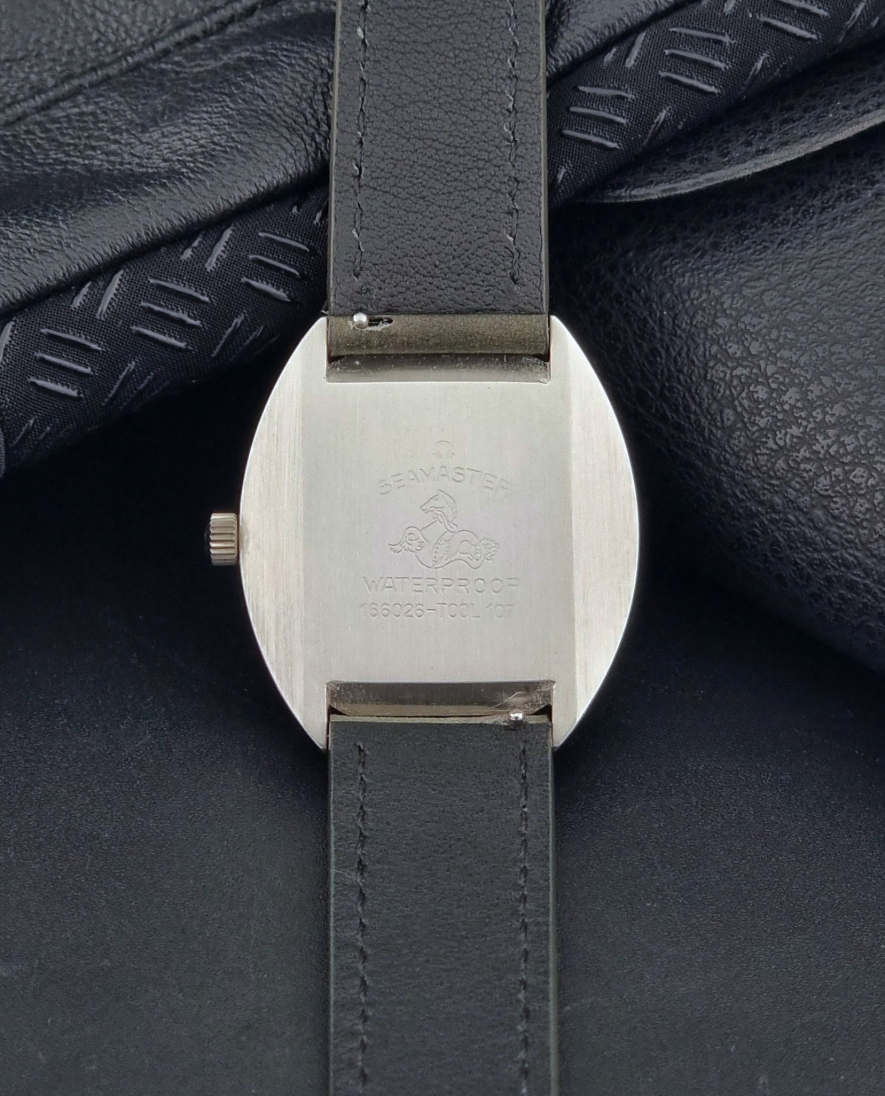 Vintage Omega Seamaster Cosmic 166.026 Wristwatch Meister Dial with leather strap on a dark gray background case back view