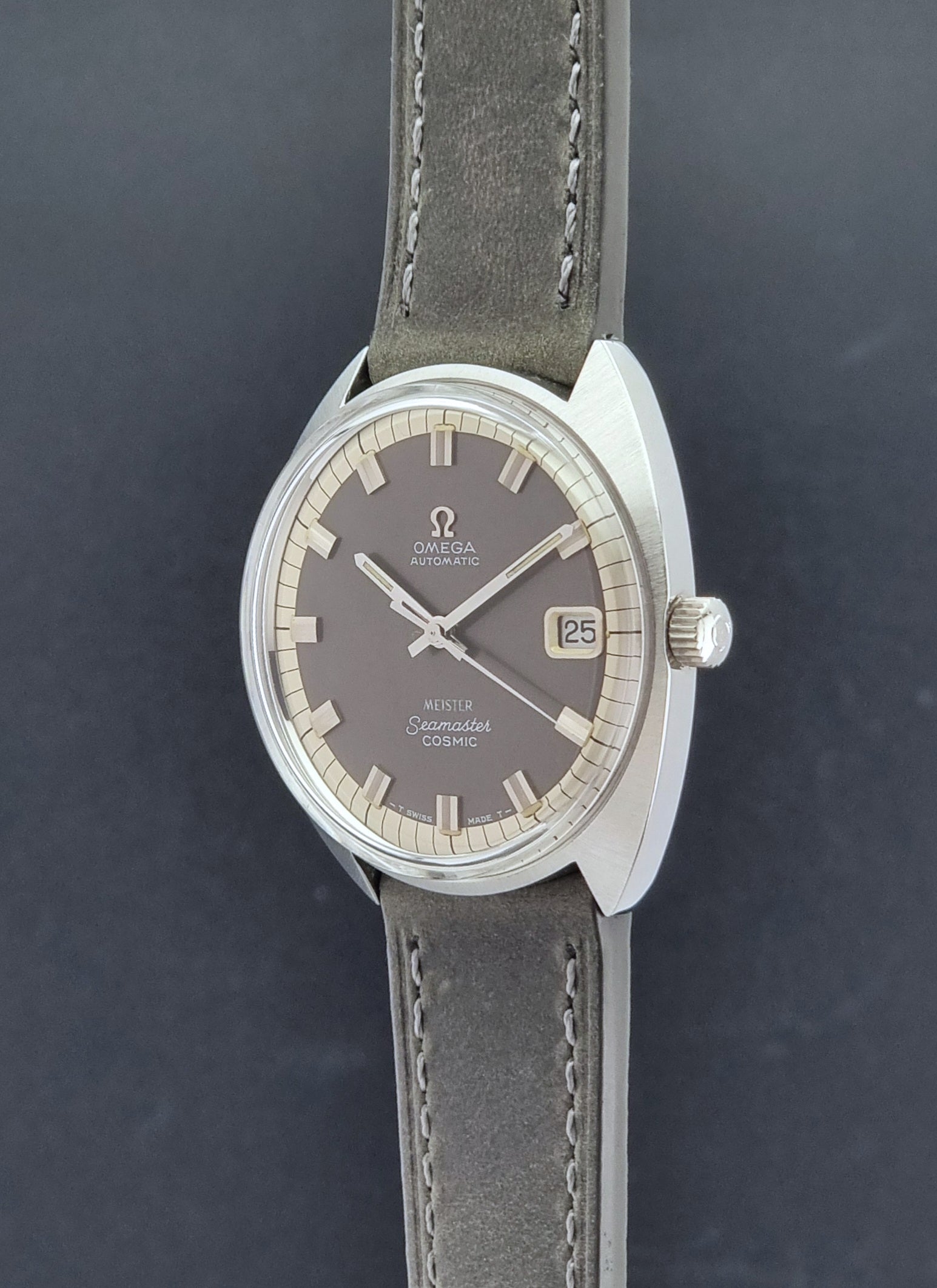 Vintage Omega Seamaster Cosmic 166.026 Wristwatch Meister Dial with leather strap on a dark gray background crown profile view