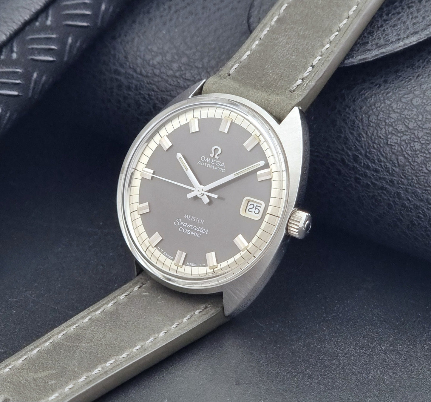 Vintage Omega Seamaster Cosmic 166.026 Wristwatch Meister Dial with leather strap on a dark gray background crown view