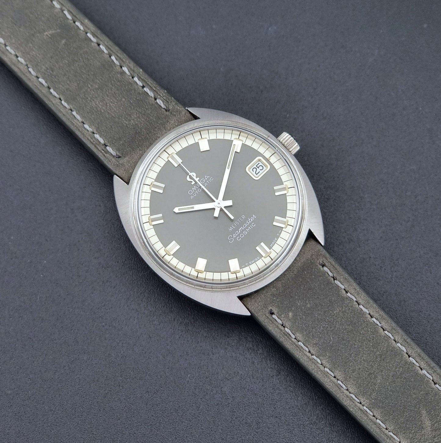 Vintage Omega Seamaster Cosmic 166.026 Wristwatch Meister Dial with leather strap on a dark gray background close up dial view
