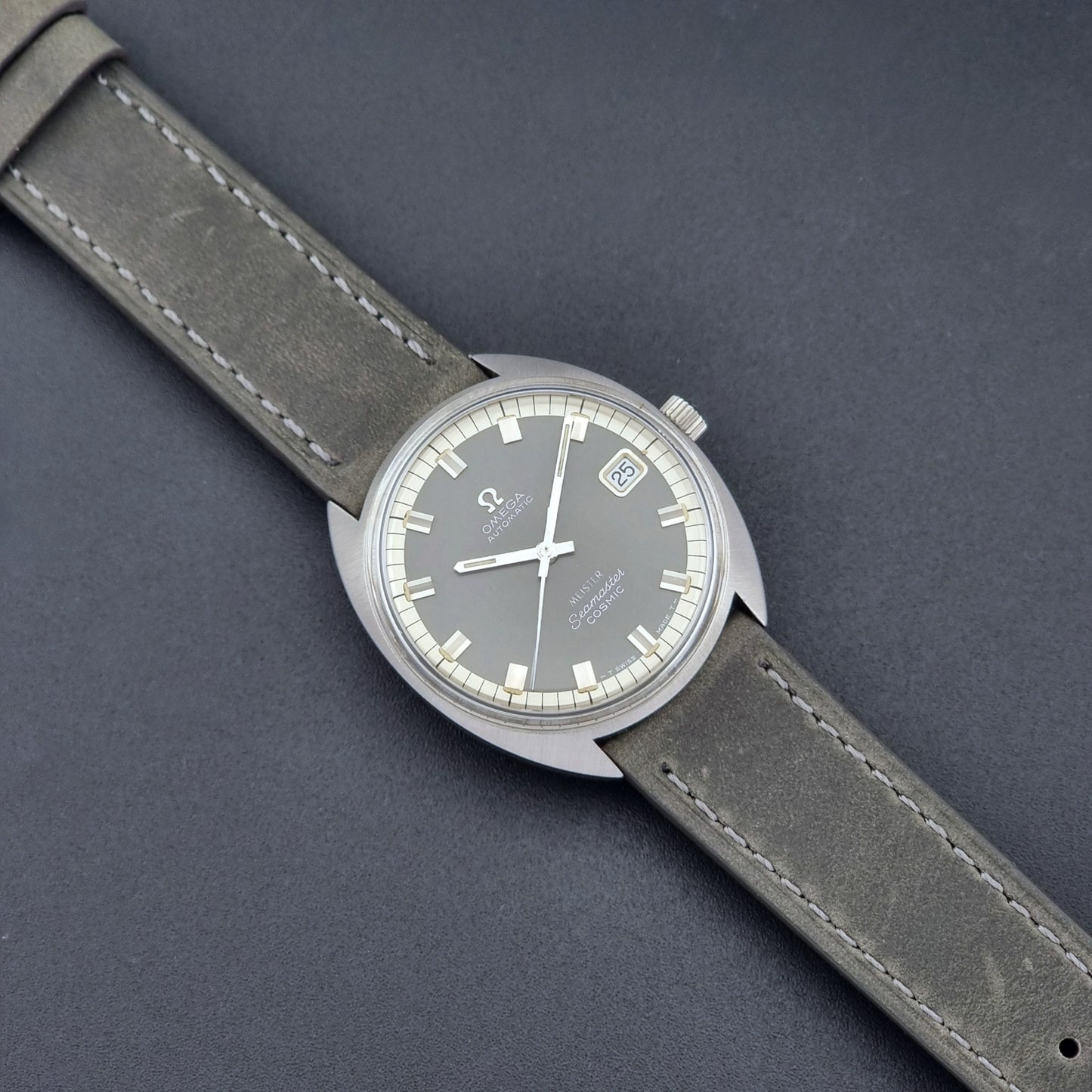 Vintage Omega Seamaster Cosmic 166.026 Wristwatch Meister Dial with leather strap on a dark gray background dial