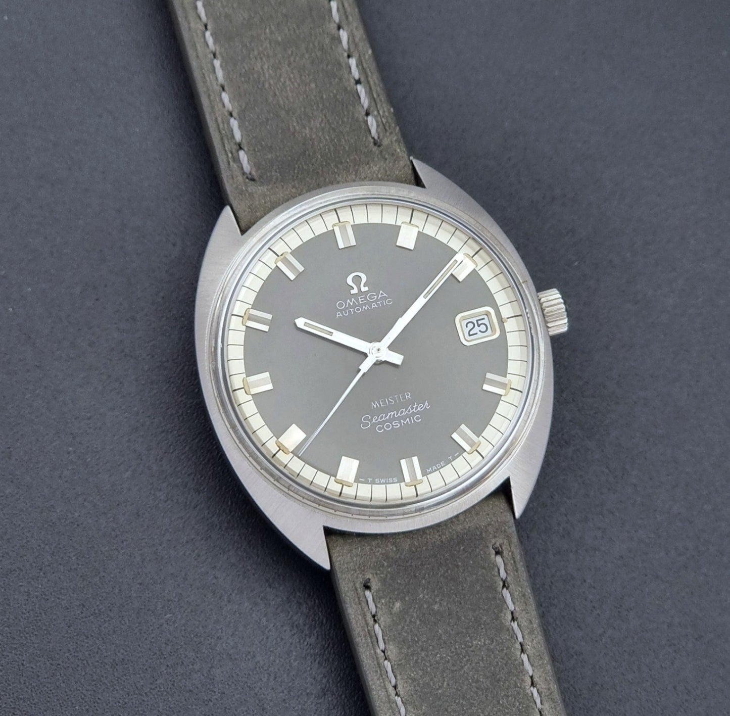Vintage Omega Seamaster Cosmic 166.026 Wristwatch Meister Dial with leather strap on a dark gray background front view